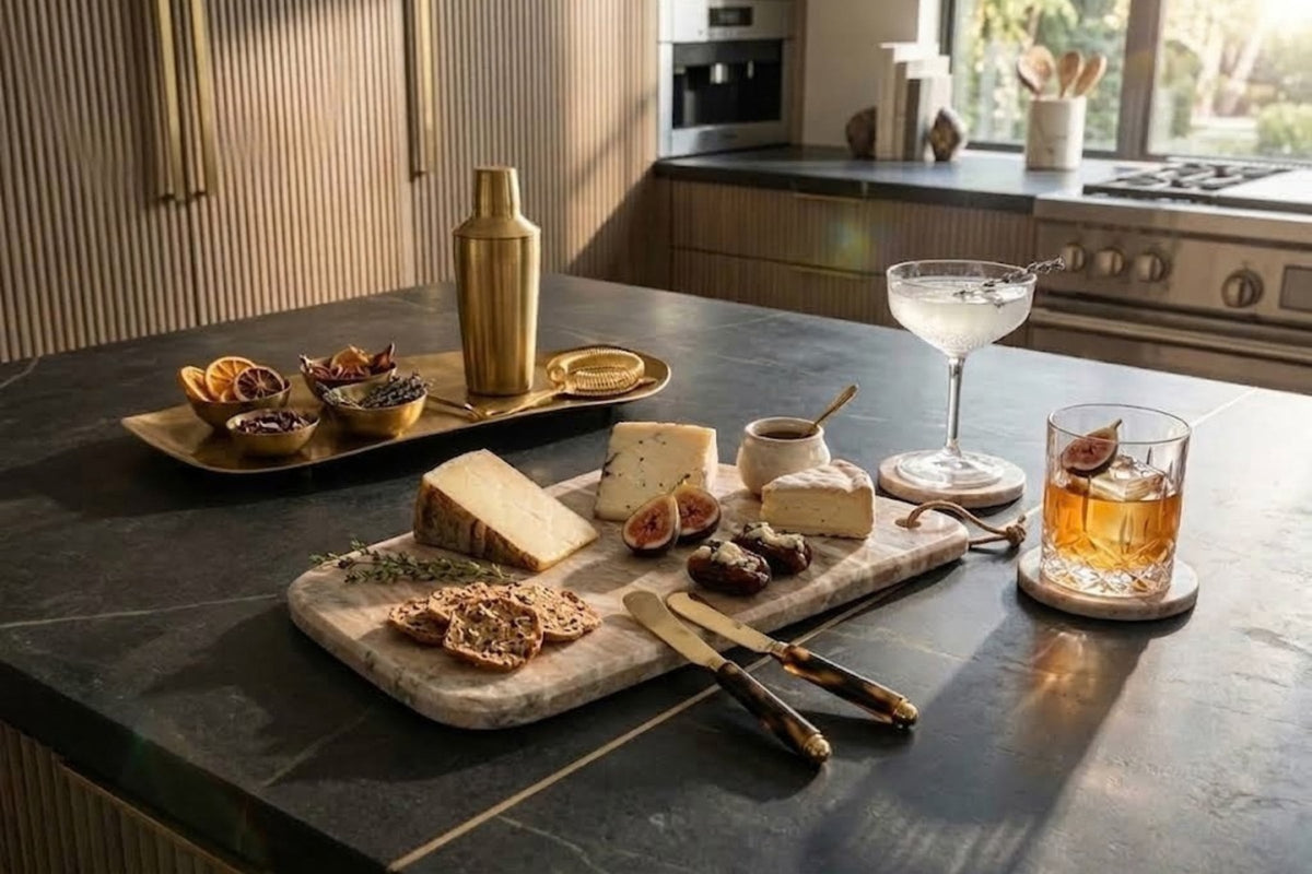 Brown-veined marble serving board set with cheese, dates and crackers on a dark stone kitchen island