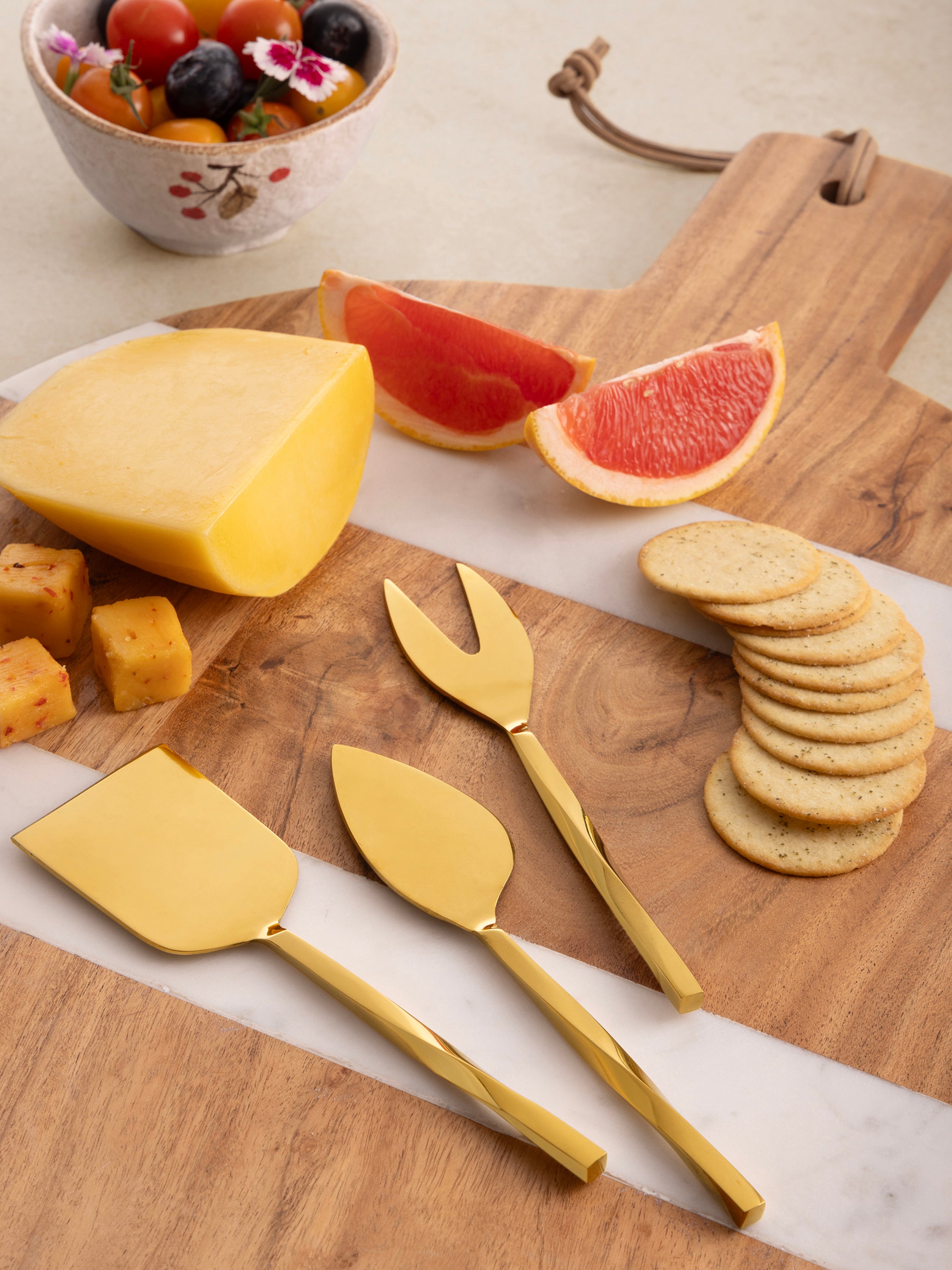Three-piece gold cheese knife set with sculptural handle detail — luxury dining accessory