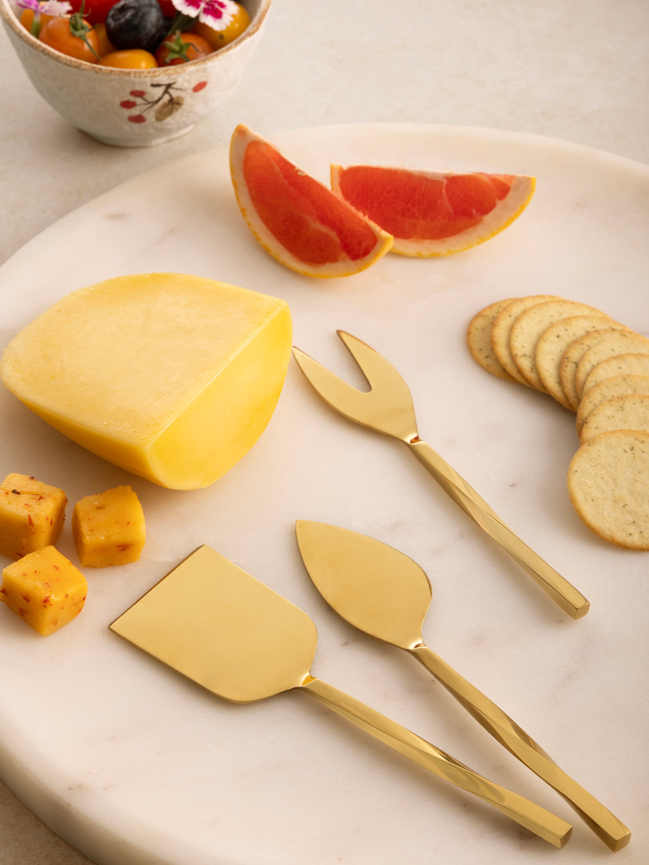 Warm gold cheese knives with twisted handles — artisan-crafted flatware essential