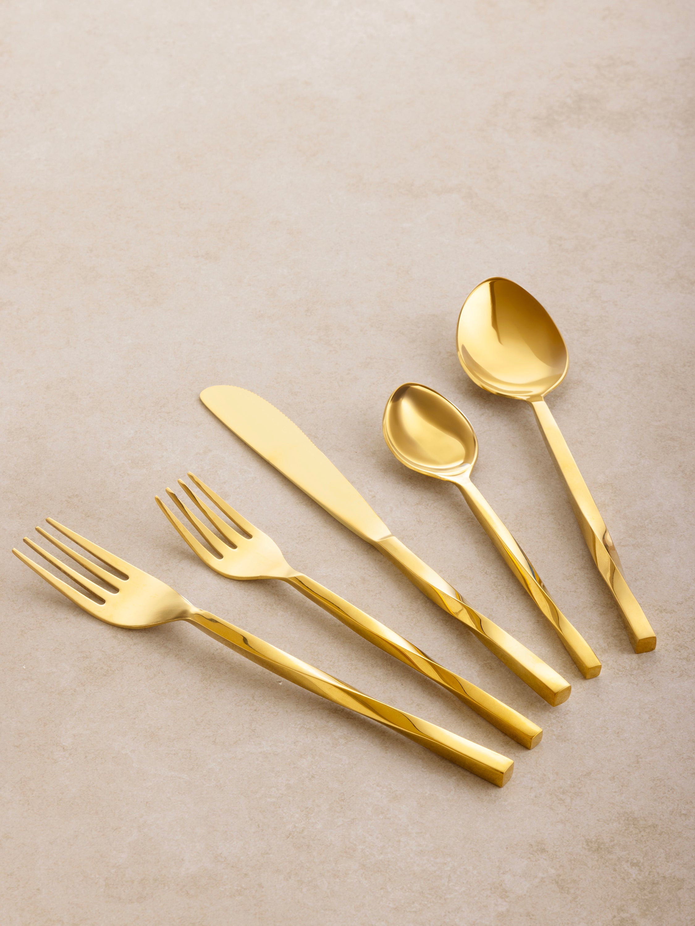 Gold flatware set with spiraled handle design — elegant five-piece place setting