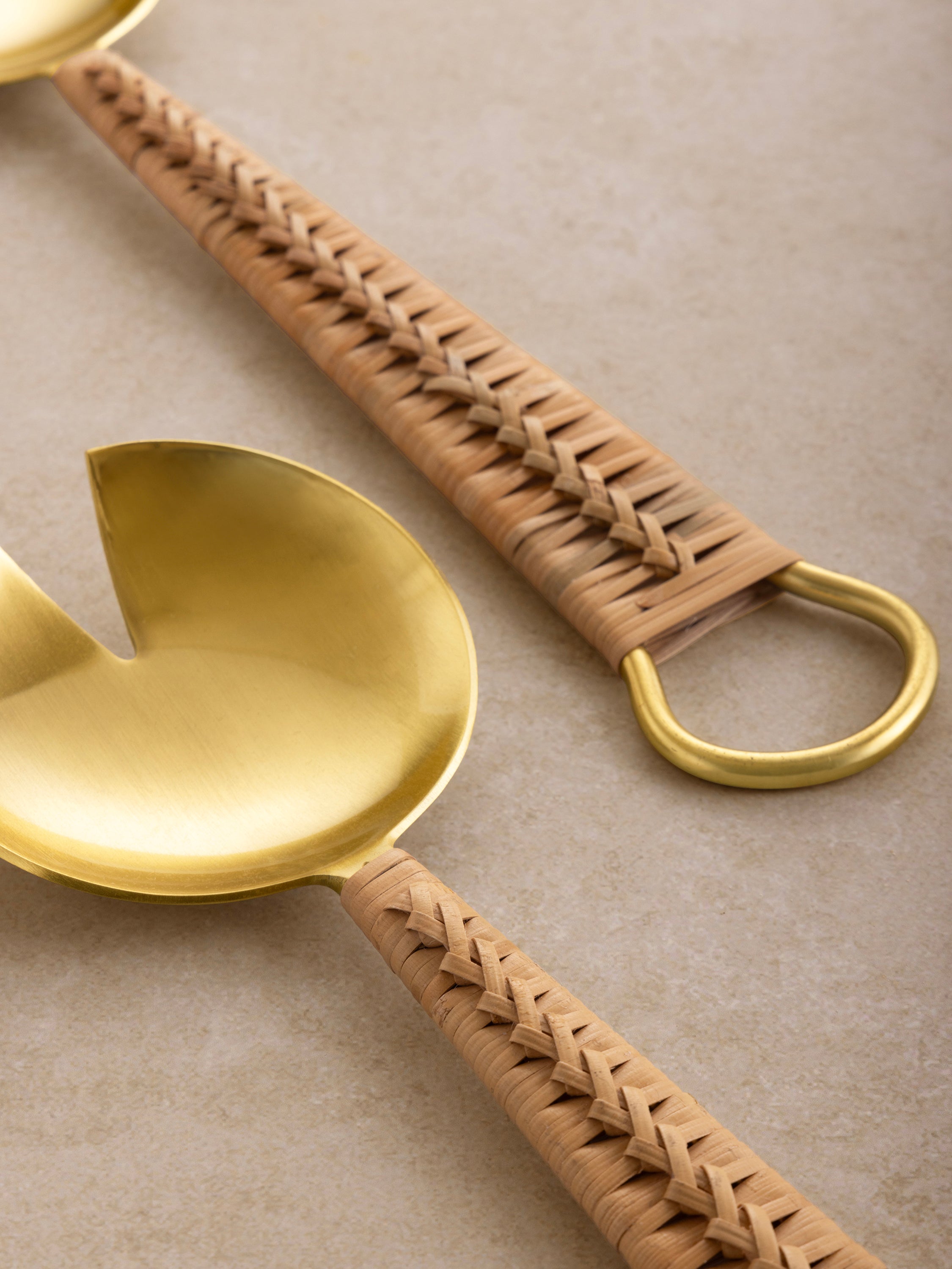 Rattan handle salad servers in matte gold finish — artisan table accessory