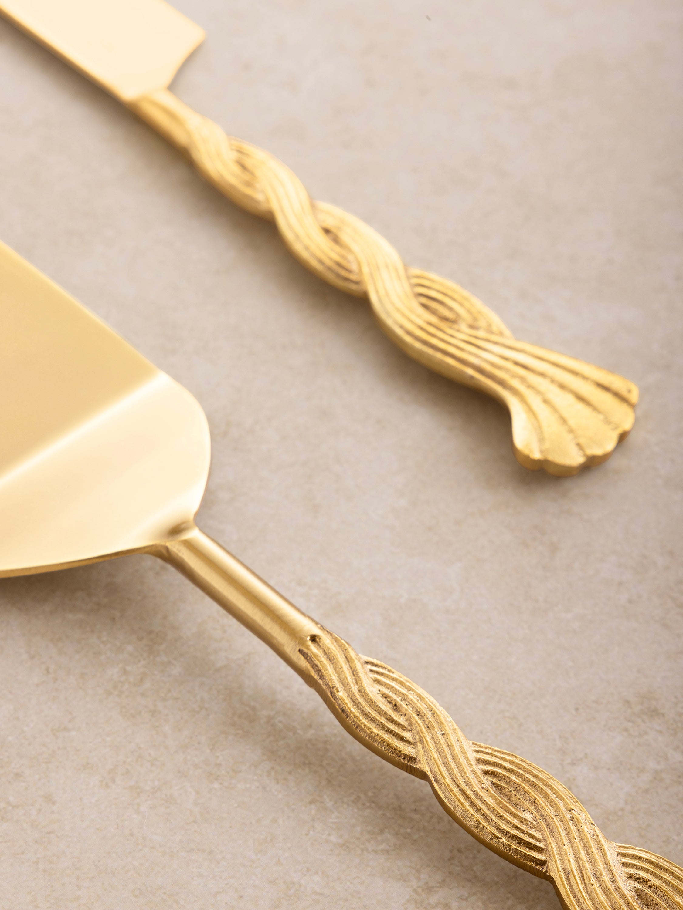 Elegant cake-serving set in matte gold with sculptural handles — timeless dining detail