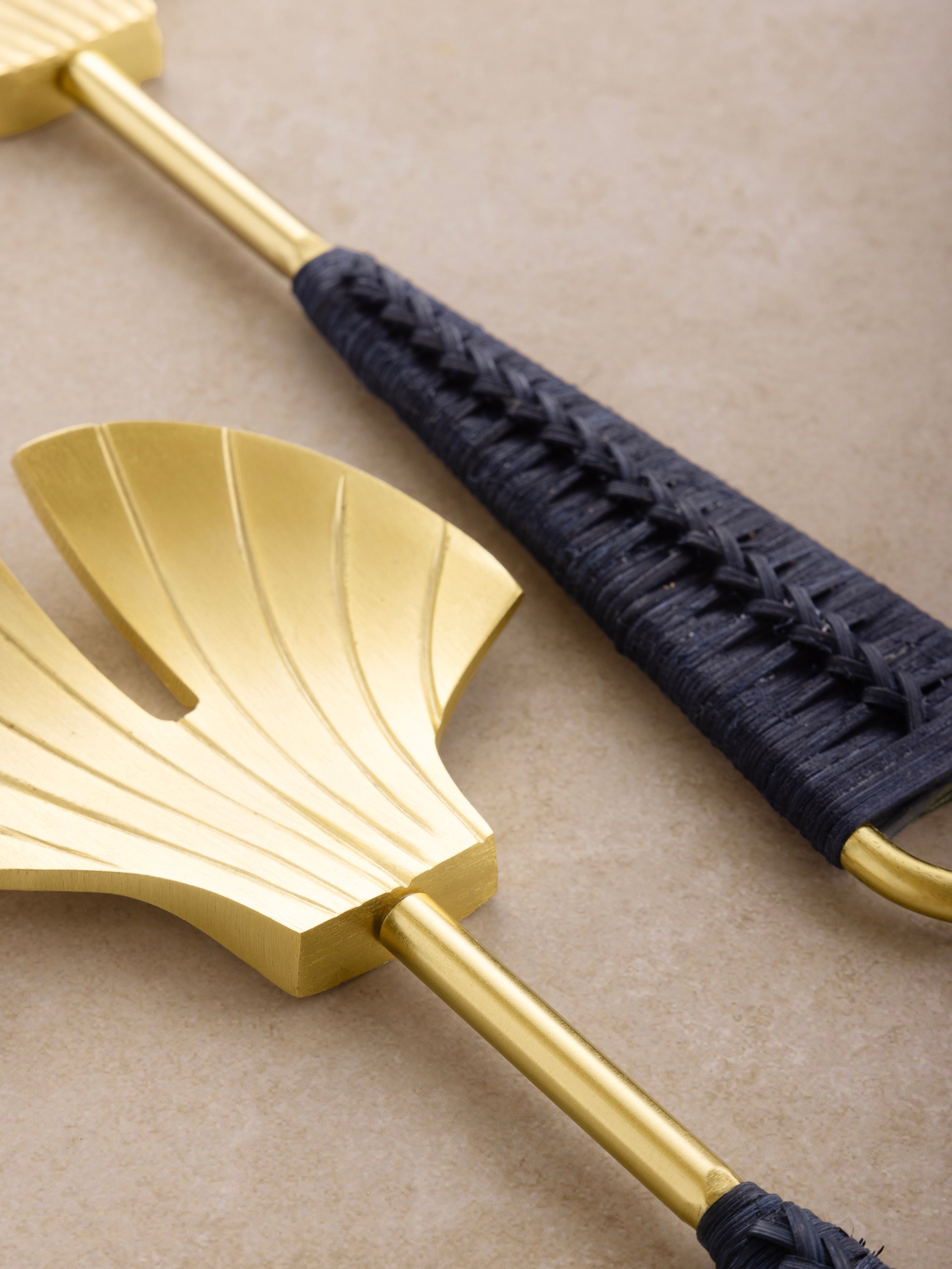 Close-up of the Vitali servers showing ridged brass fan heads, textured handles, and smooth polished finish.