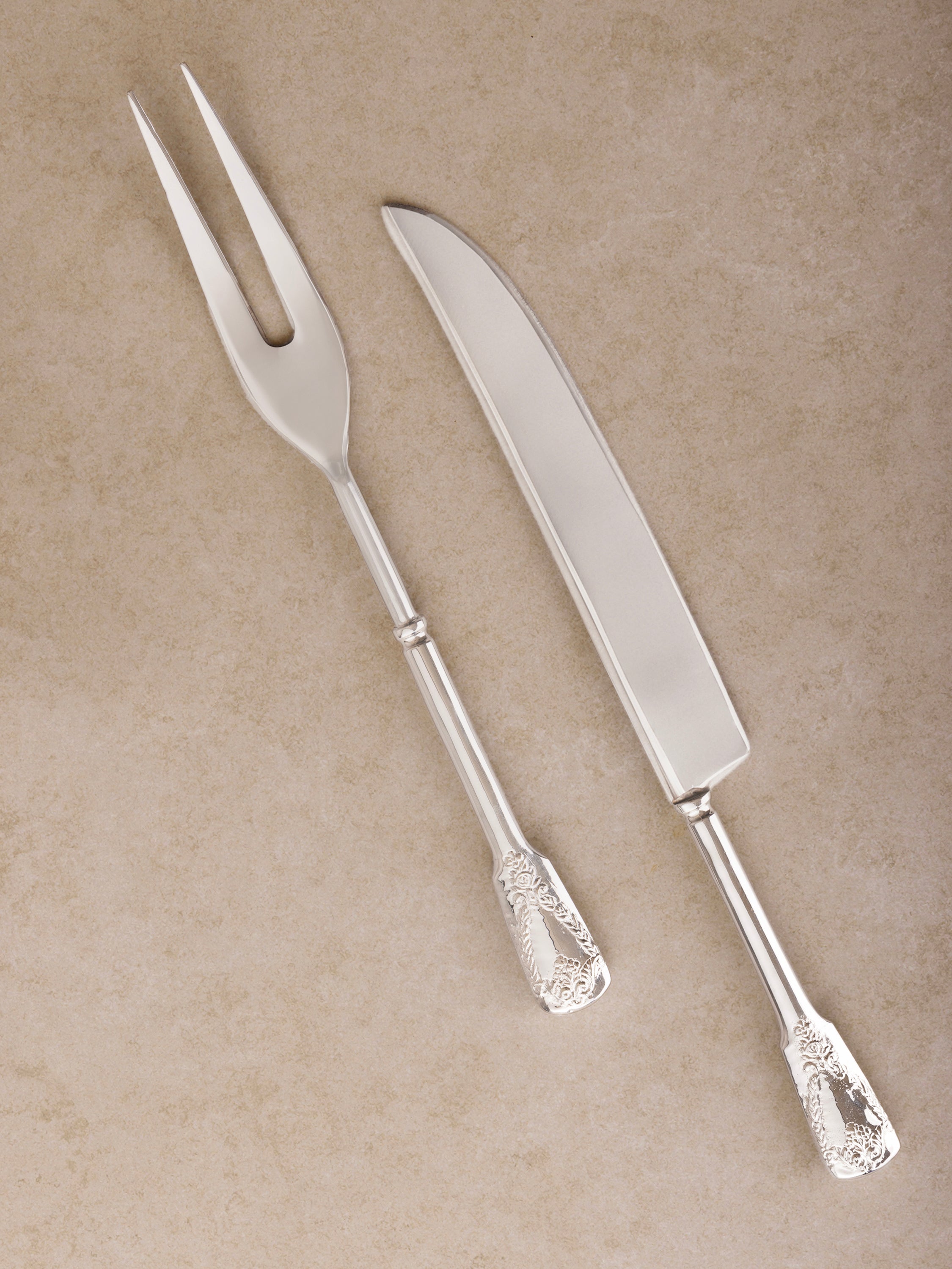 Glossy silver carving knife and fork set with embossed handles — luxury dining essential