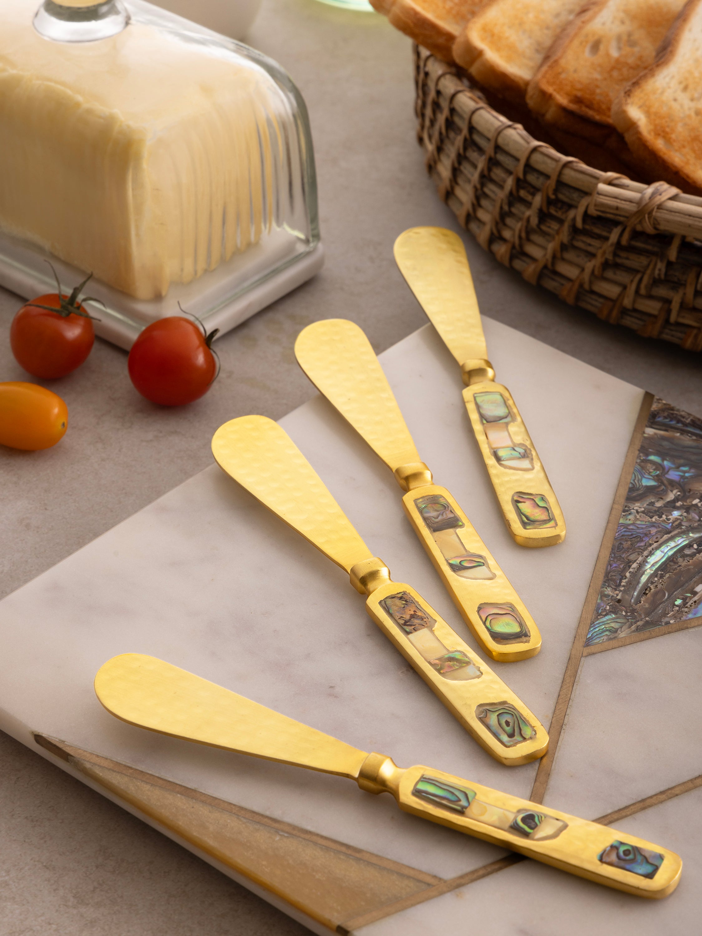 Gold-finish butter spreads with luminous shell handles — elegant dining accent