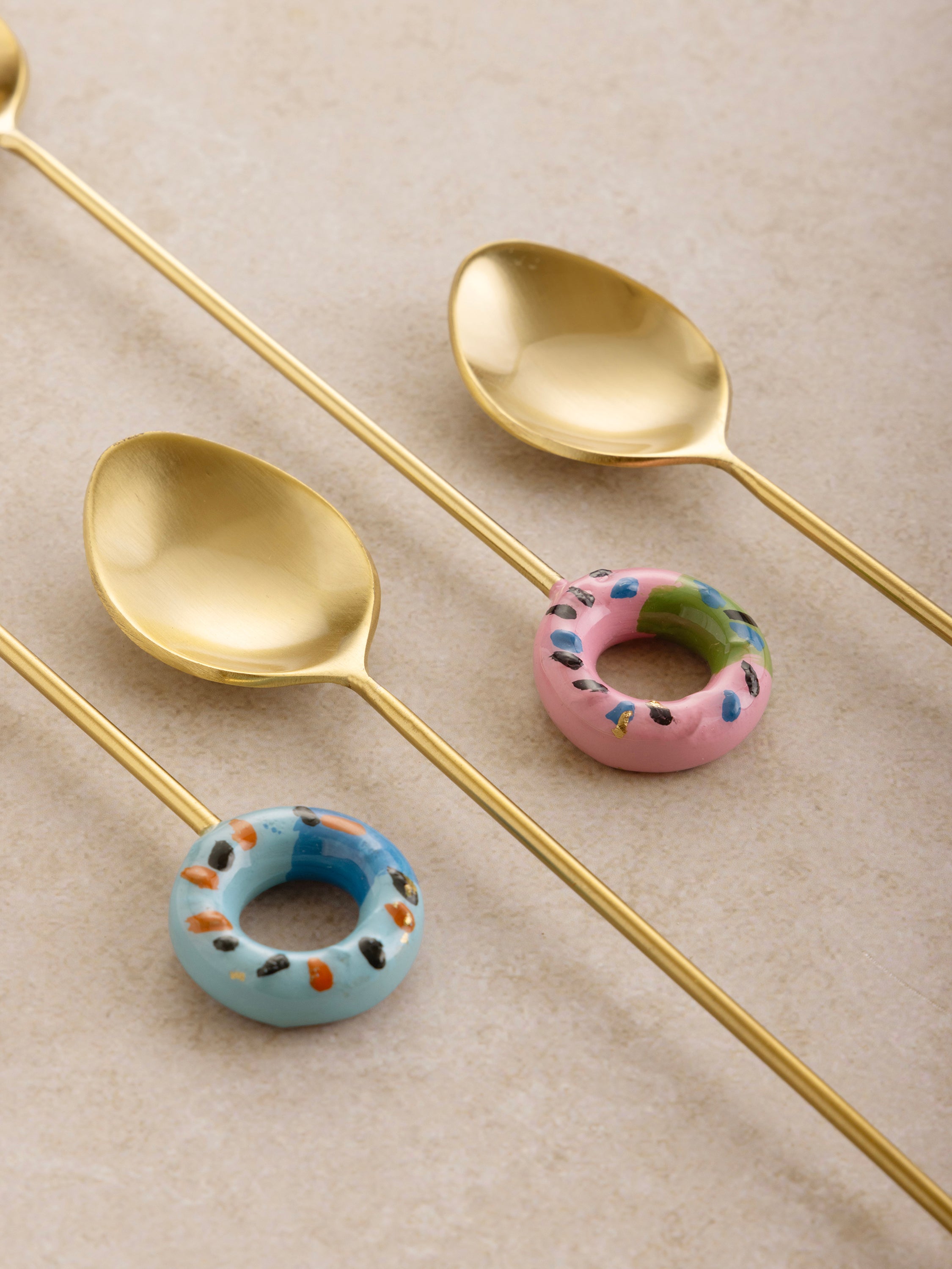 Stylish gold-finish teaspoons with handcrafted ceramic handles, perfect for tea and desserts