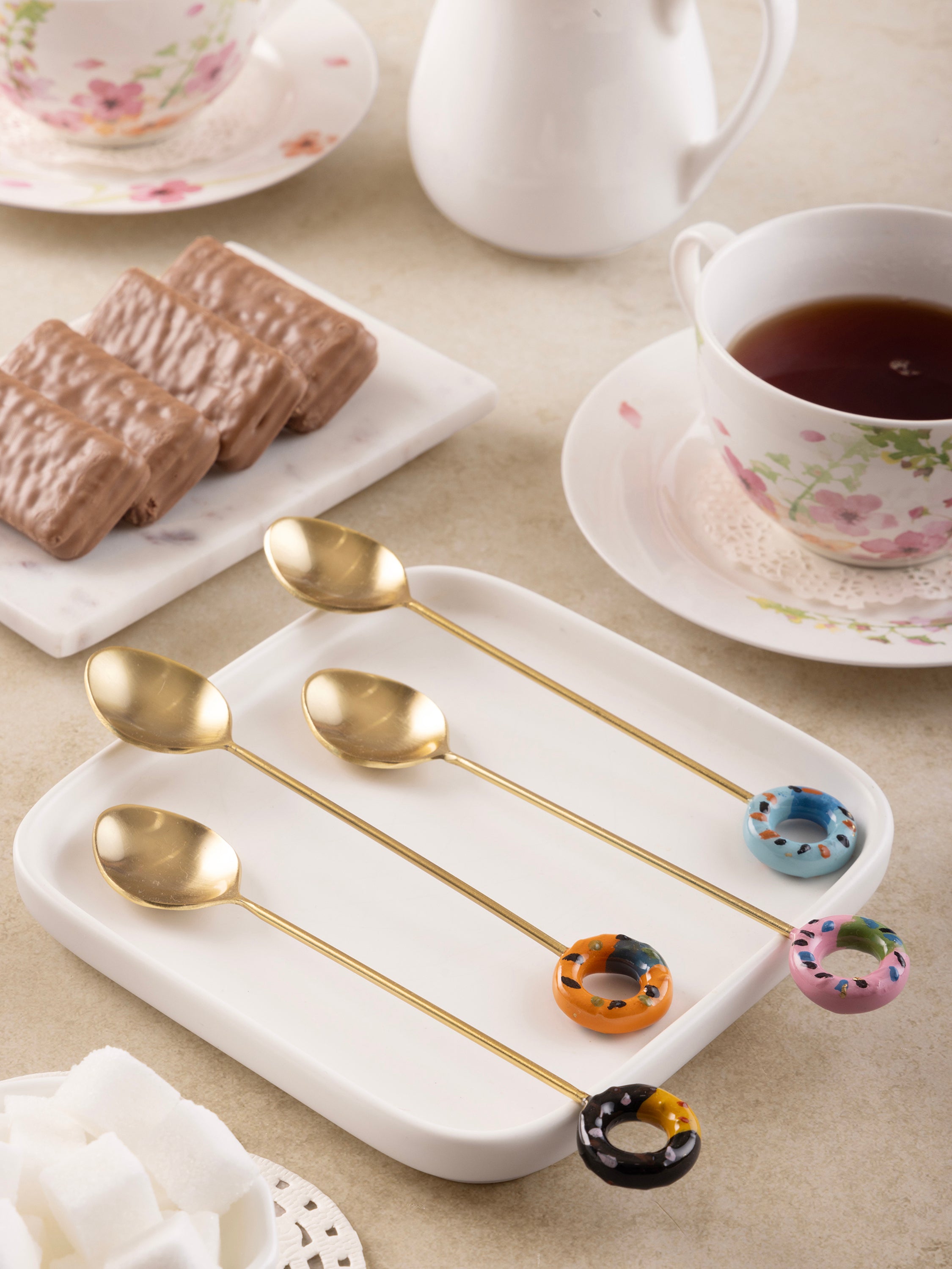 Unique designer gold teaspoons featuring colorful ceramic donut handles for a playful touch