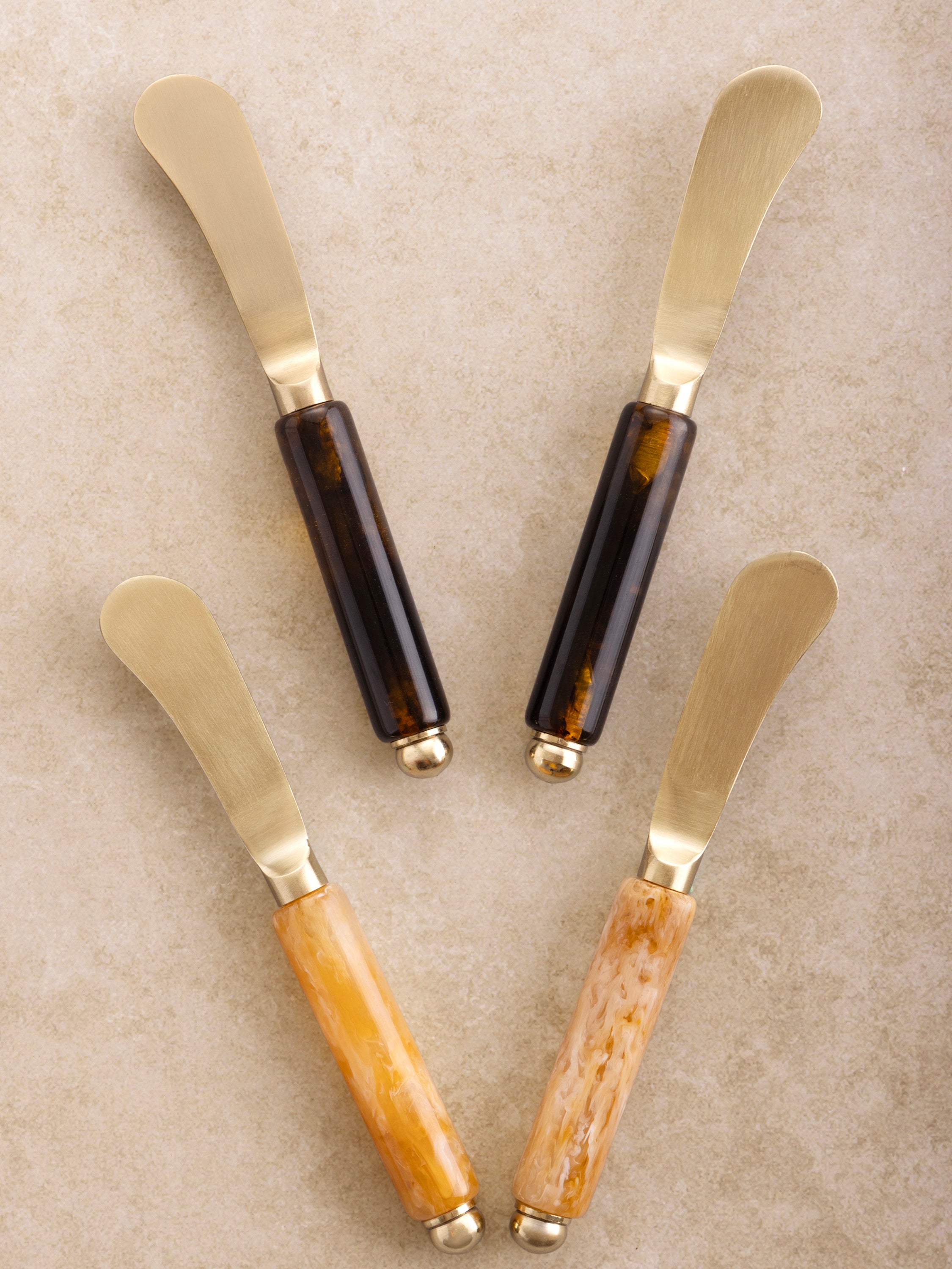 Set of four butter knives with brown resin handles and matte gold blades
