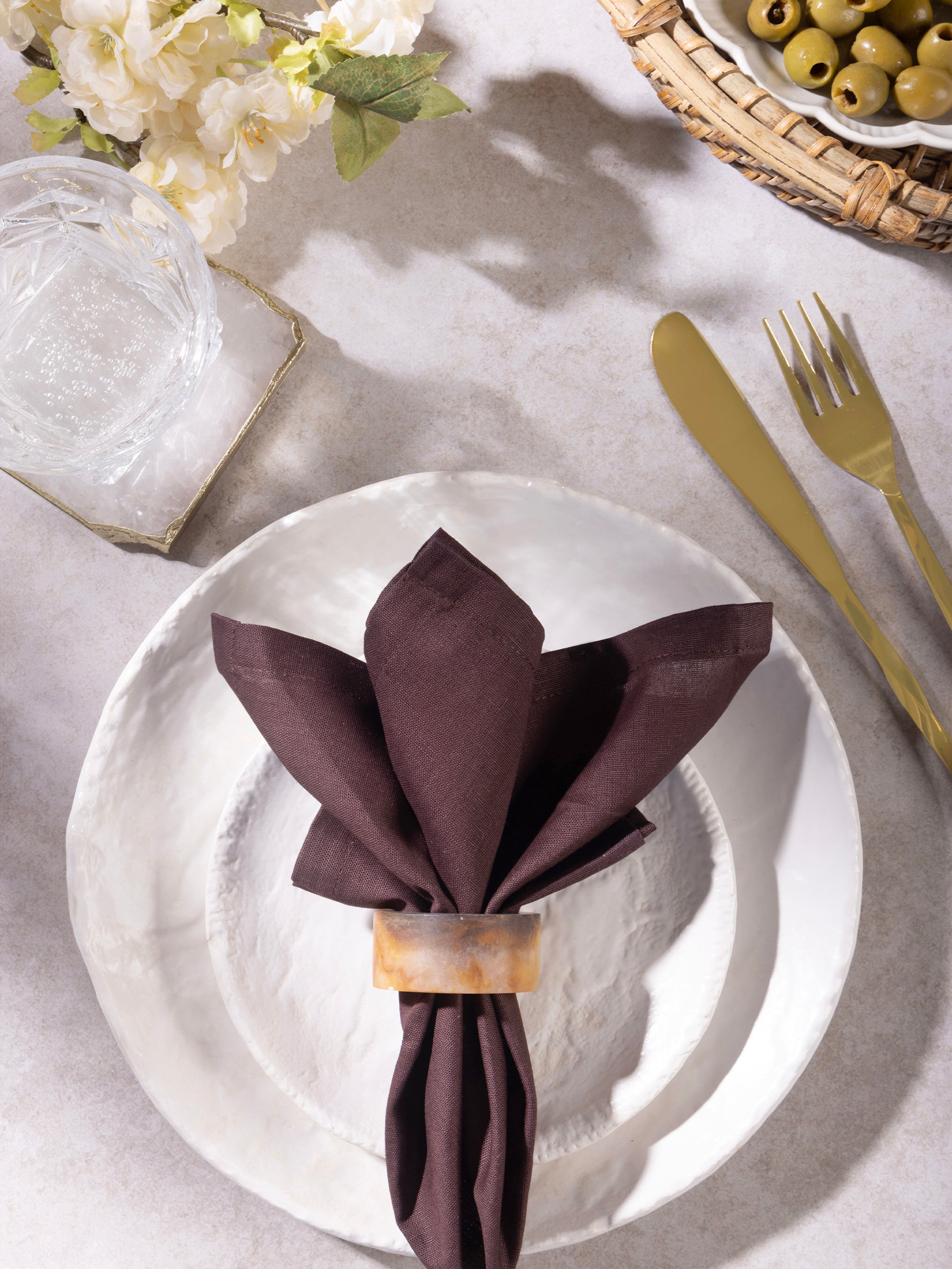 Resin napkin ring in amber tones holding a folded napkin on a plate setting, highlighting color depth and table presentation