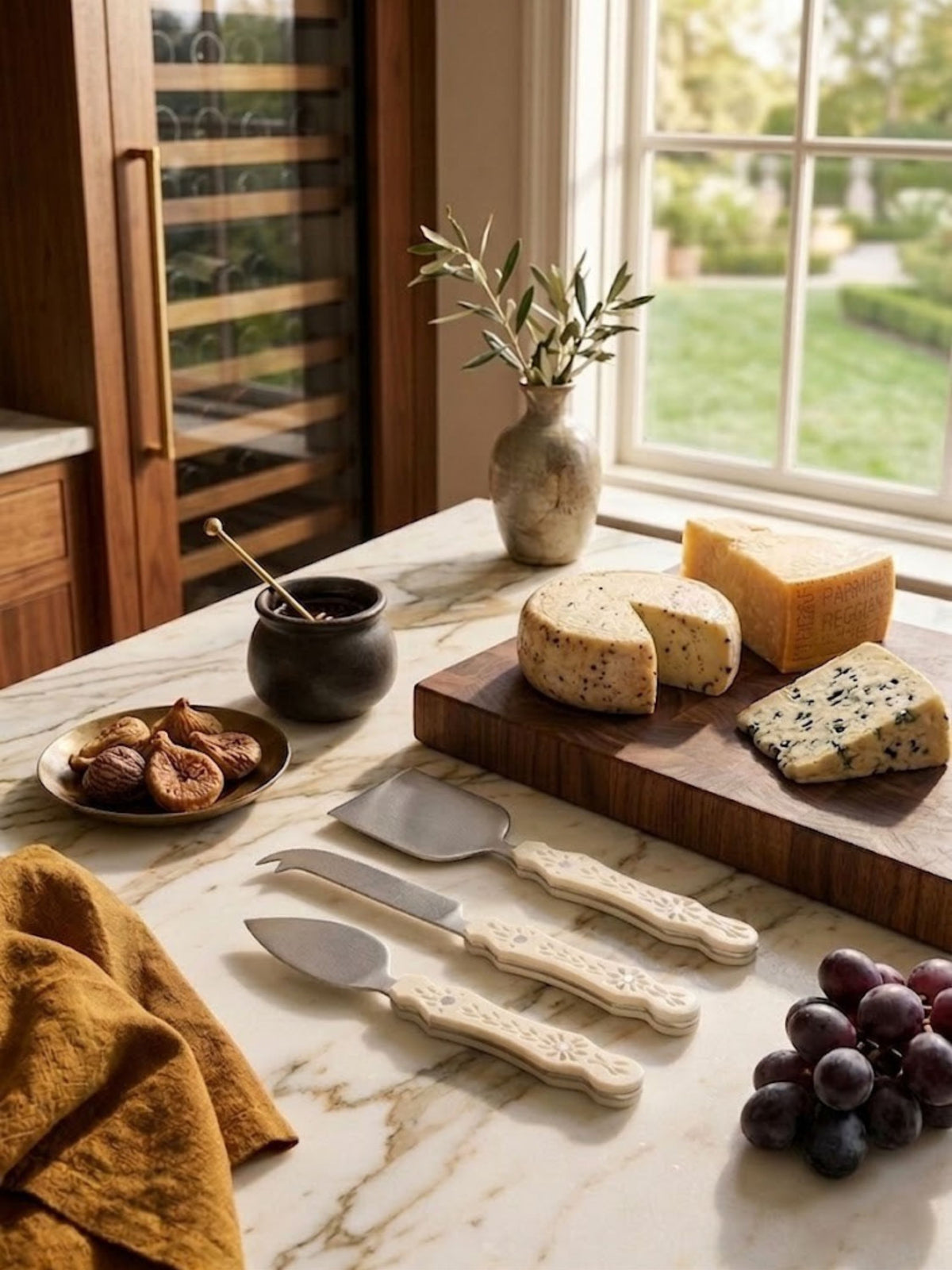 Ivory carved resin cheese knives with pierced botanical handle detailing, shown on a kitchen counter.