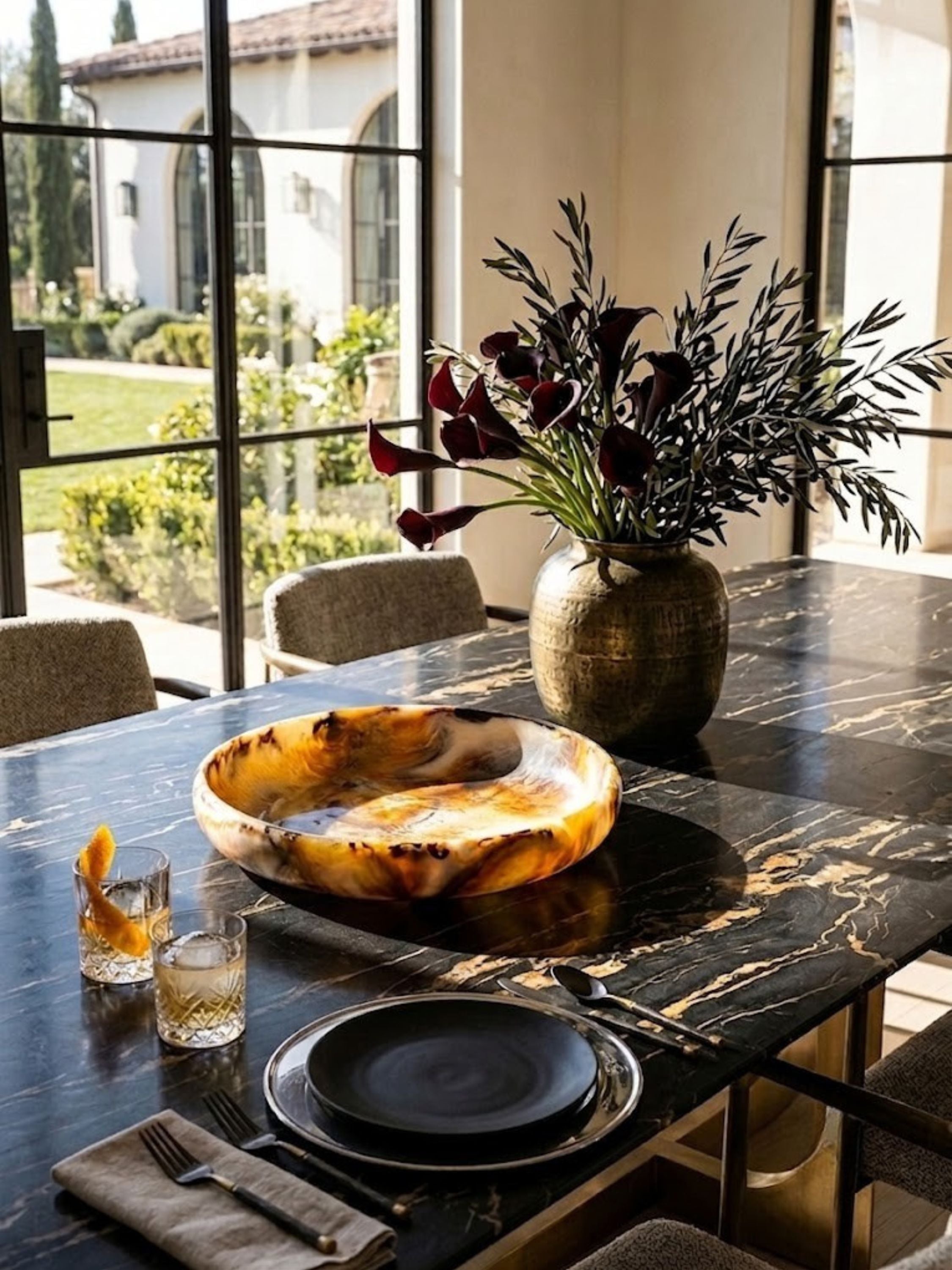 Marbled resin bowl in amber and ivory tones, styled on a dining table beside lit candles.