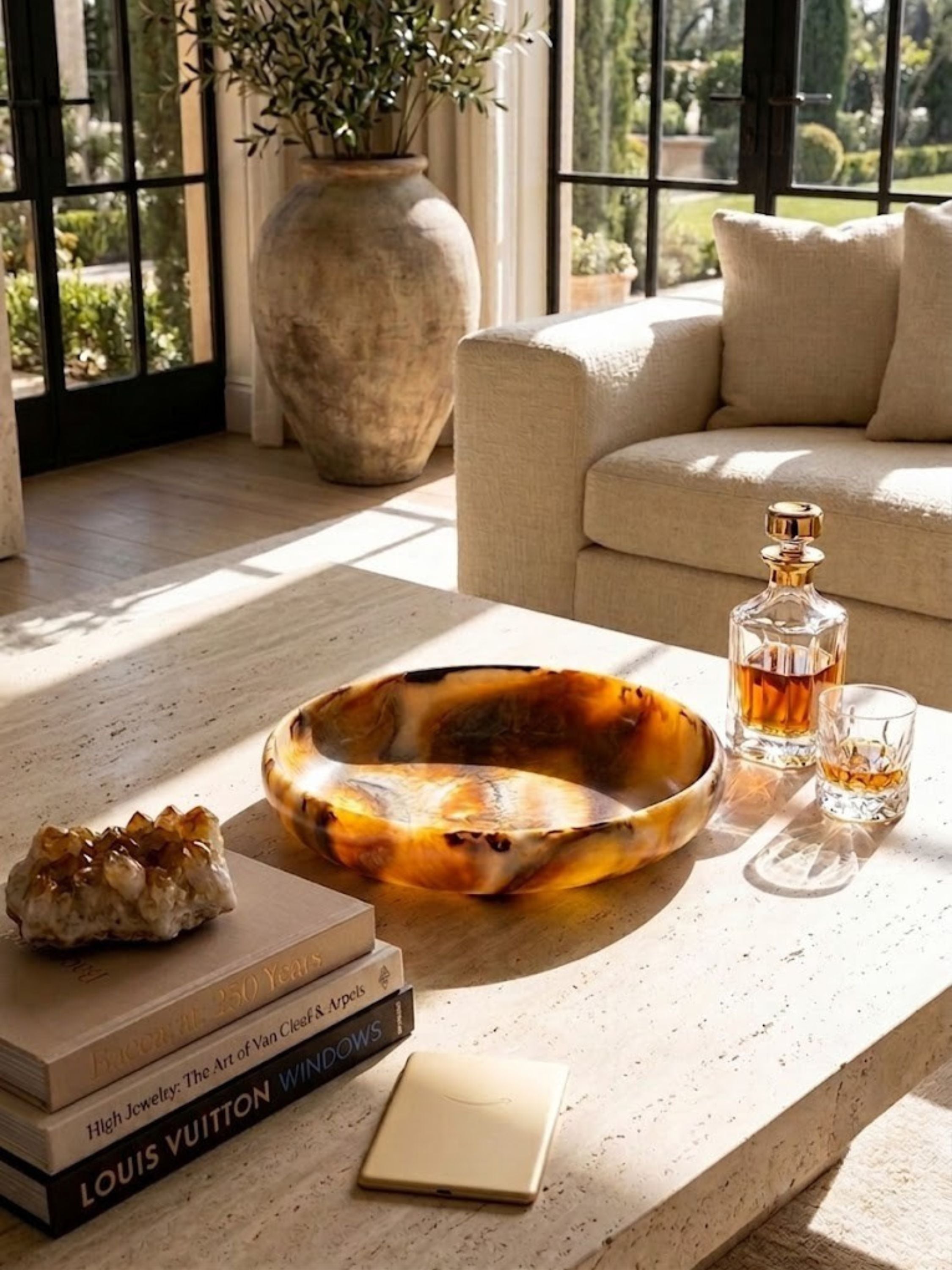 Marbled resin bowl in deep amber tones, styled on a coffee table surface in evening light.