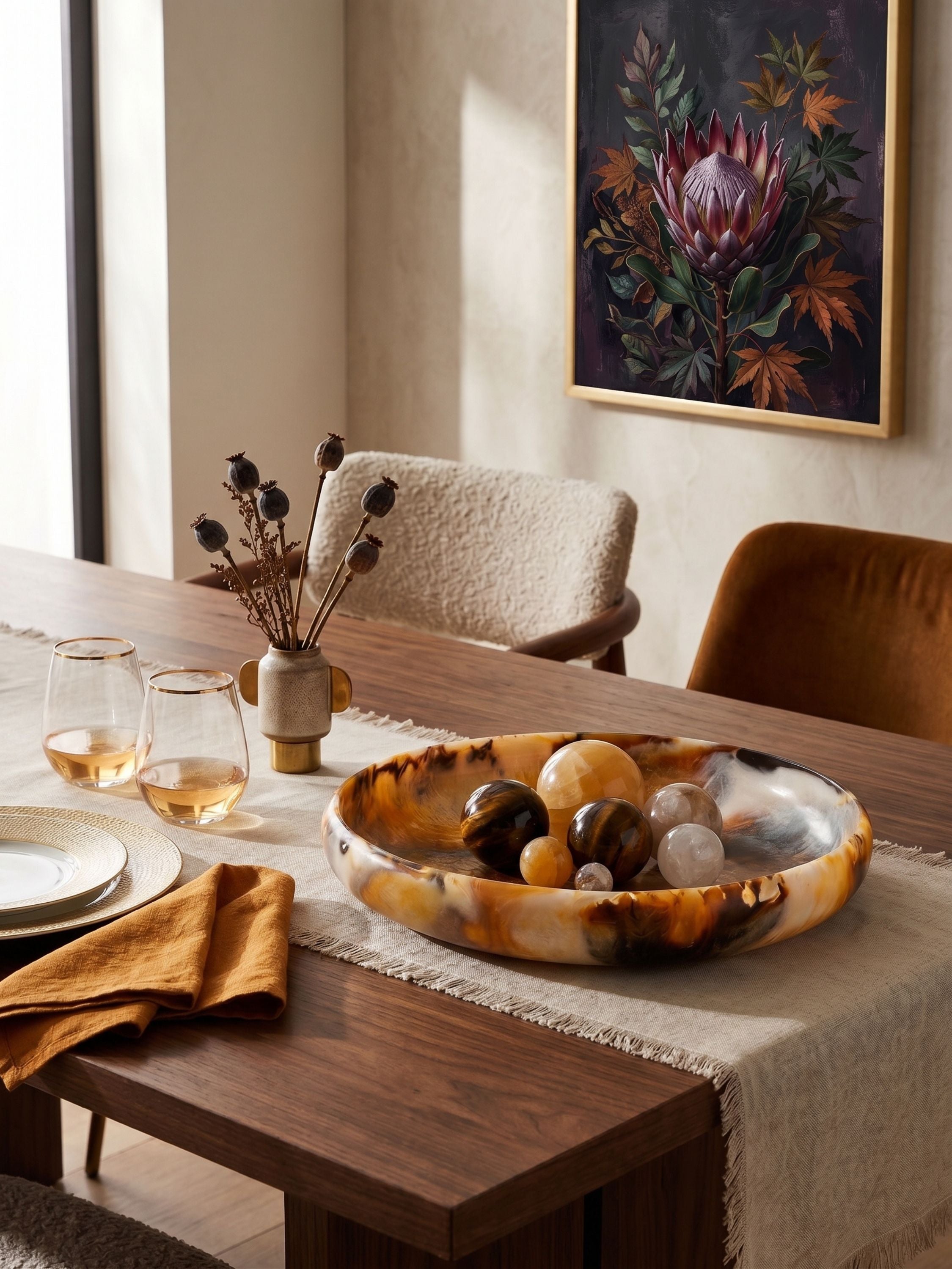 Amber swirl resin decorative bowl styled on a dining table with glassware and linens in a warm, elevated dining setting