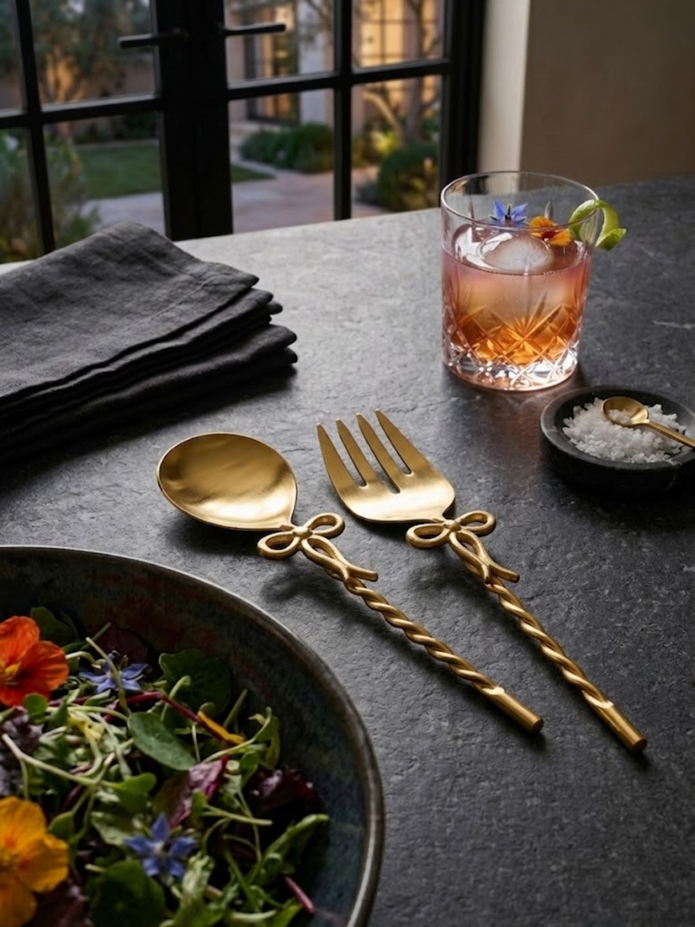 Imperial gold salad servers paired with cocktails and tableware, showing their twisted gold handles.