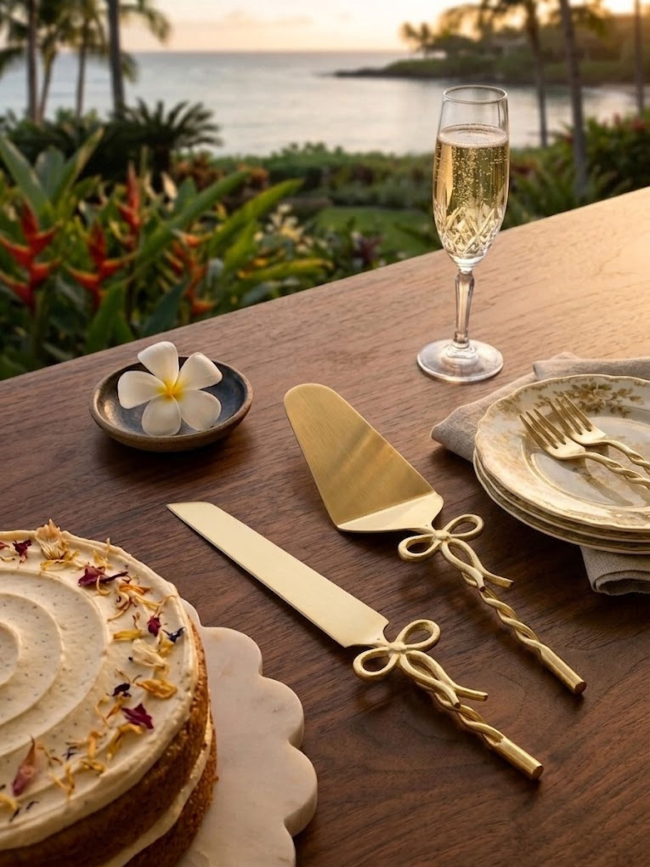 Imperial gold cake servers presented on a coastal-inspired dining table with champagne and dessert.