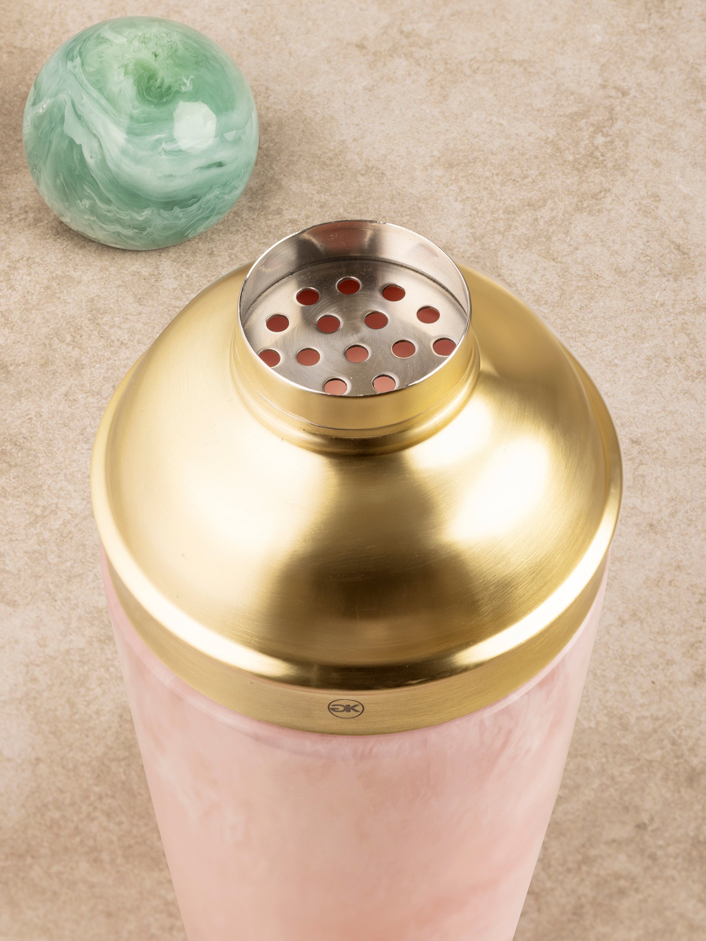 Close-up of Copenhagen cocktail shaker components showing brass lid detail, green knob finial, and marbled resin body
