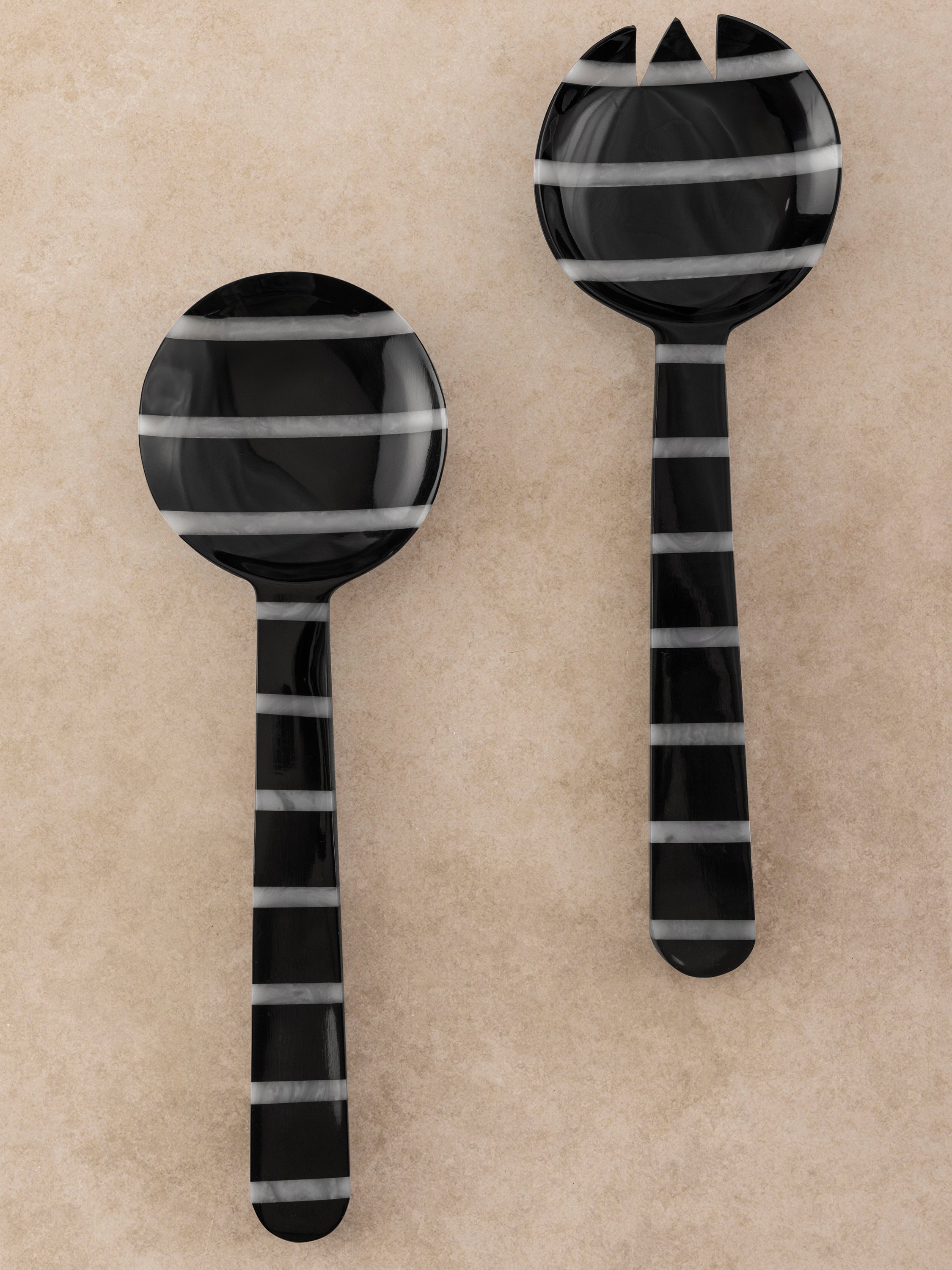 Set of two resin salad servers with bold black and white striped handles shown in a clean top-down composition