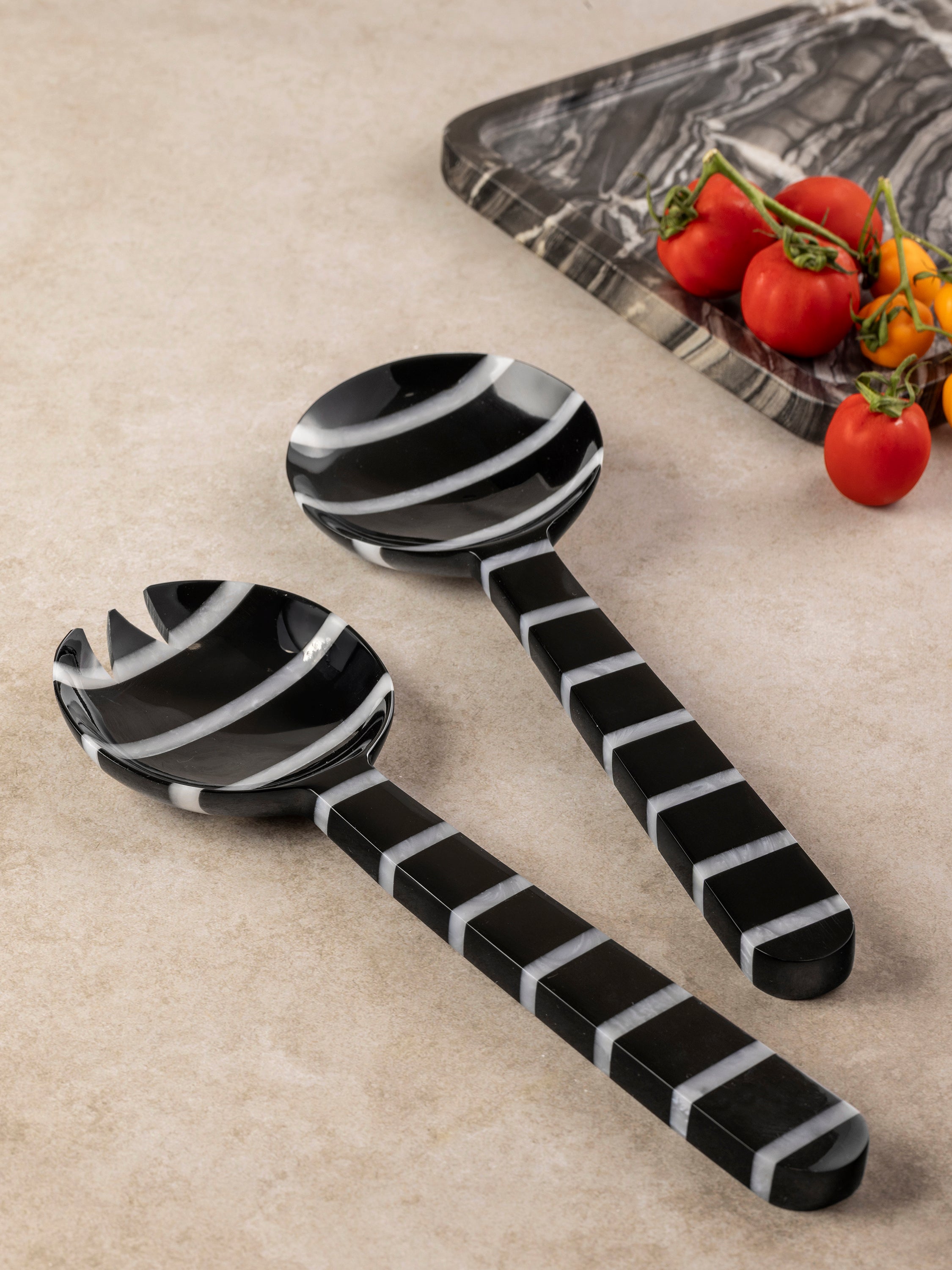 Cox salad servers arranged for serving, showing rounded stainless steel heads and striped resin handle form