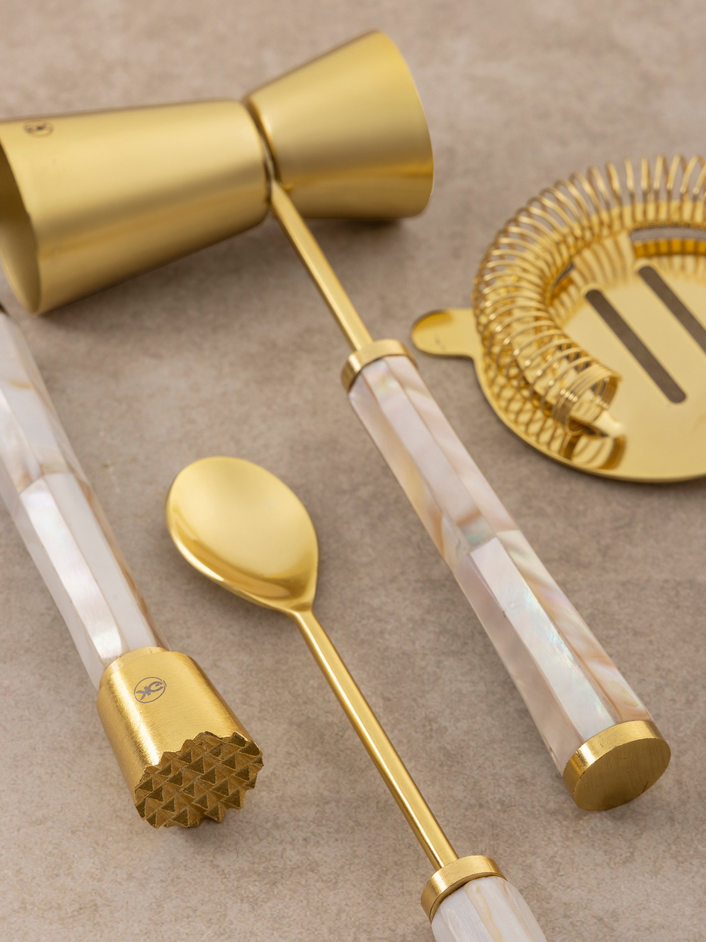 Close-up of Darzi bar tool handle showing mother of pearl surface with soft iridescent sheen and brass stem connection
