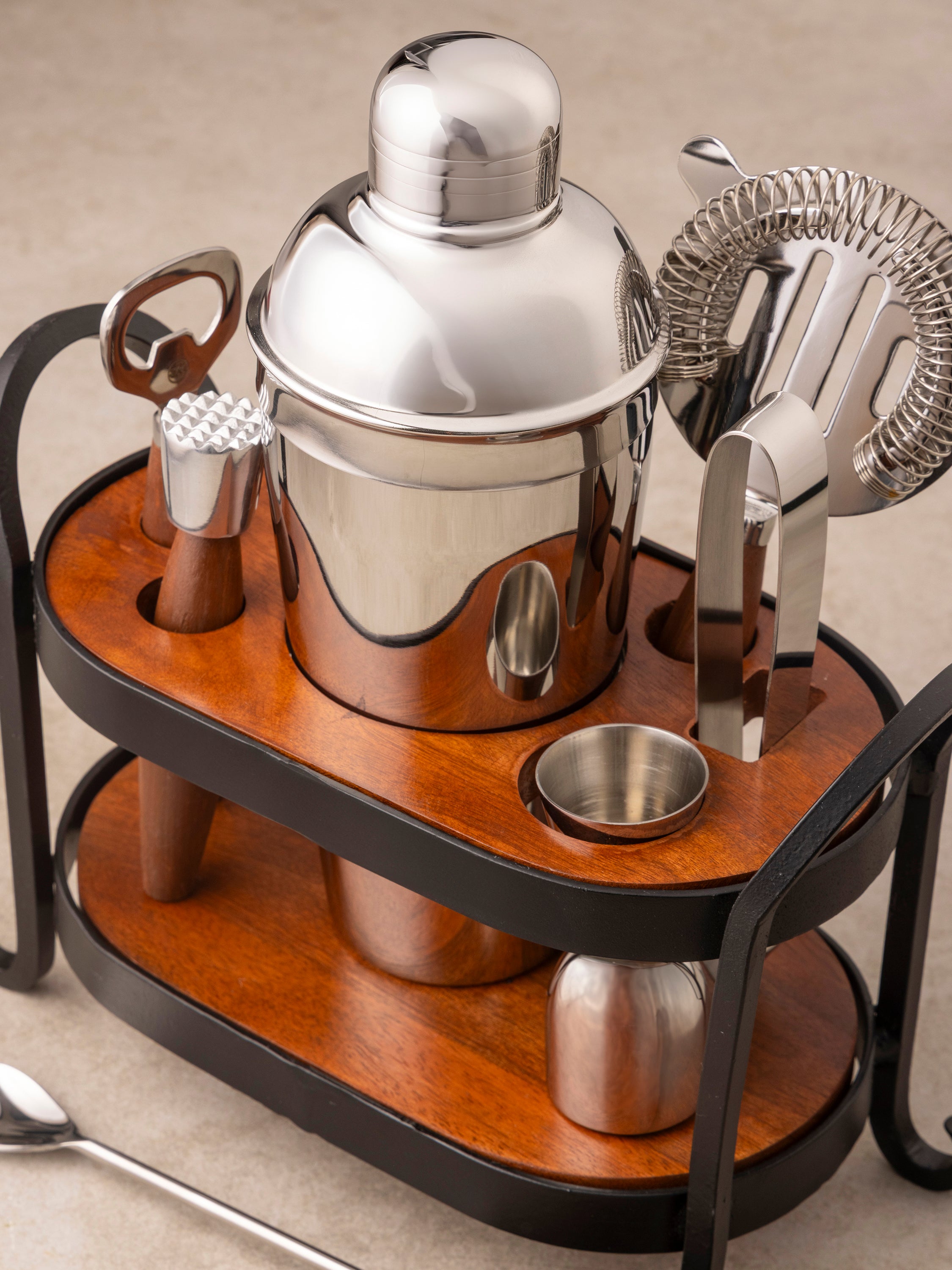 Charley bar tools arranged showing shaker, jigger, bar spoon, and stand with warm stainless steel and wood detailing