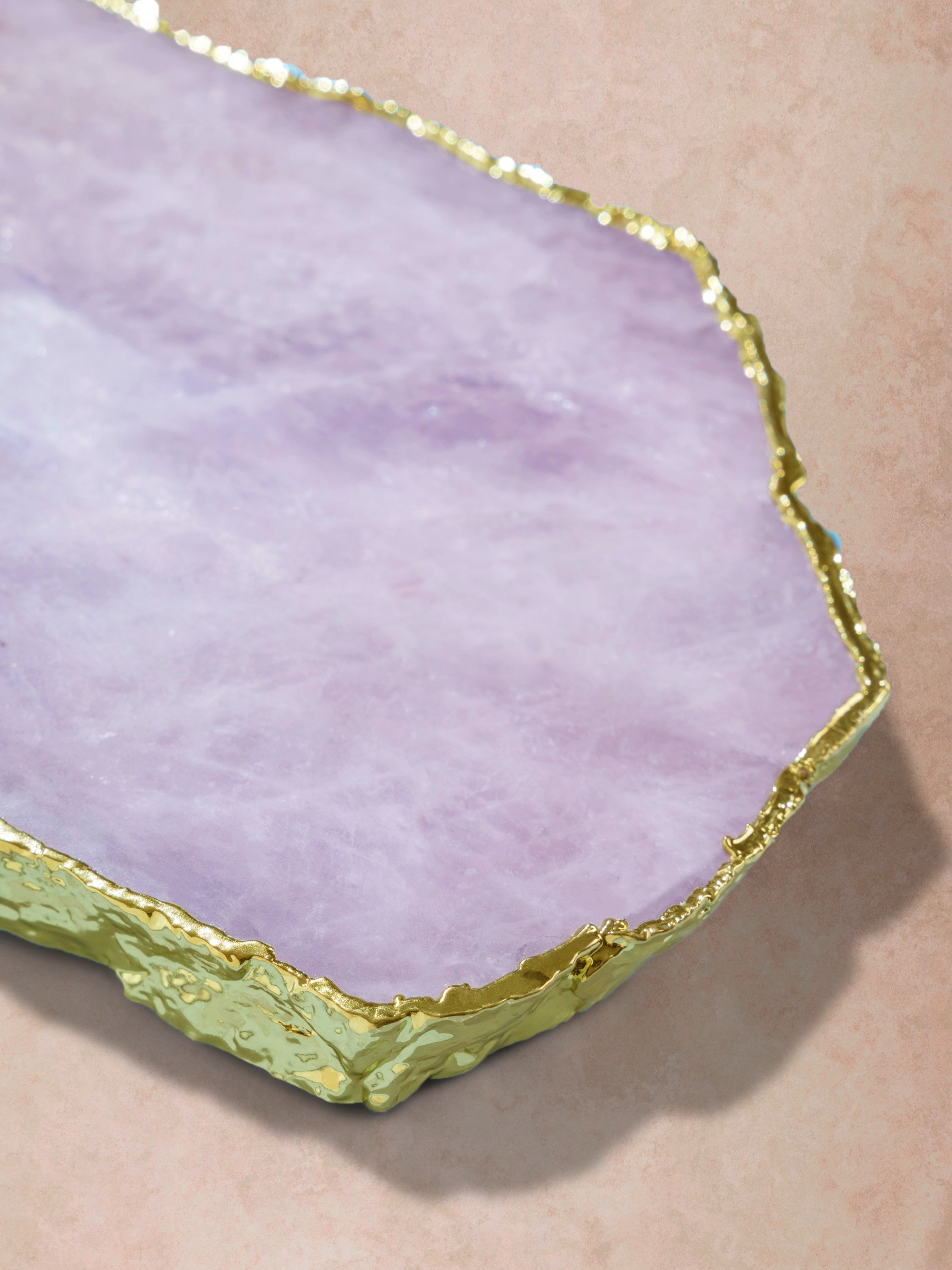 Close-up of rose quartz slab showing soft mineral clouding, polished surface, and irregular gold-edged perimeter