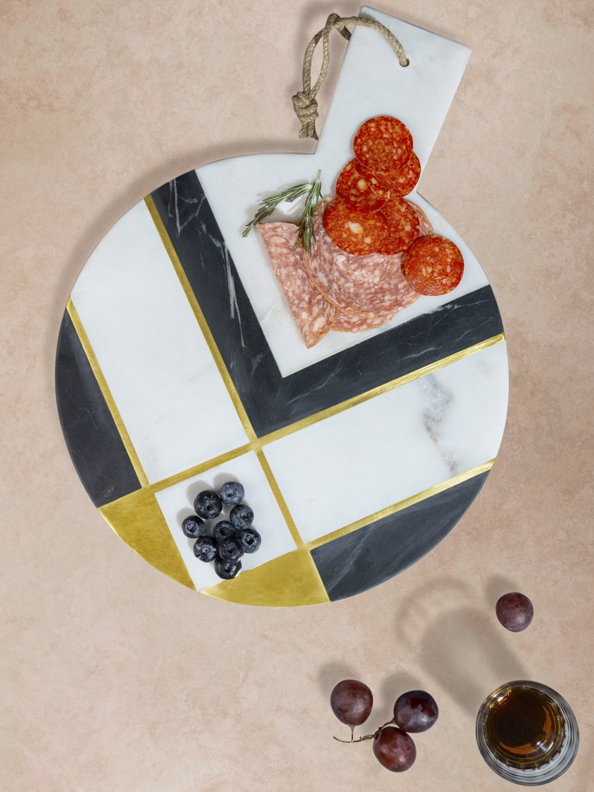 Marble cheese board with segmented geometric pattern holding appetizers, highlighting polished surface, circular form, and color-blocked stone composition