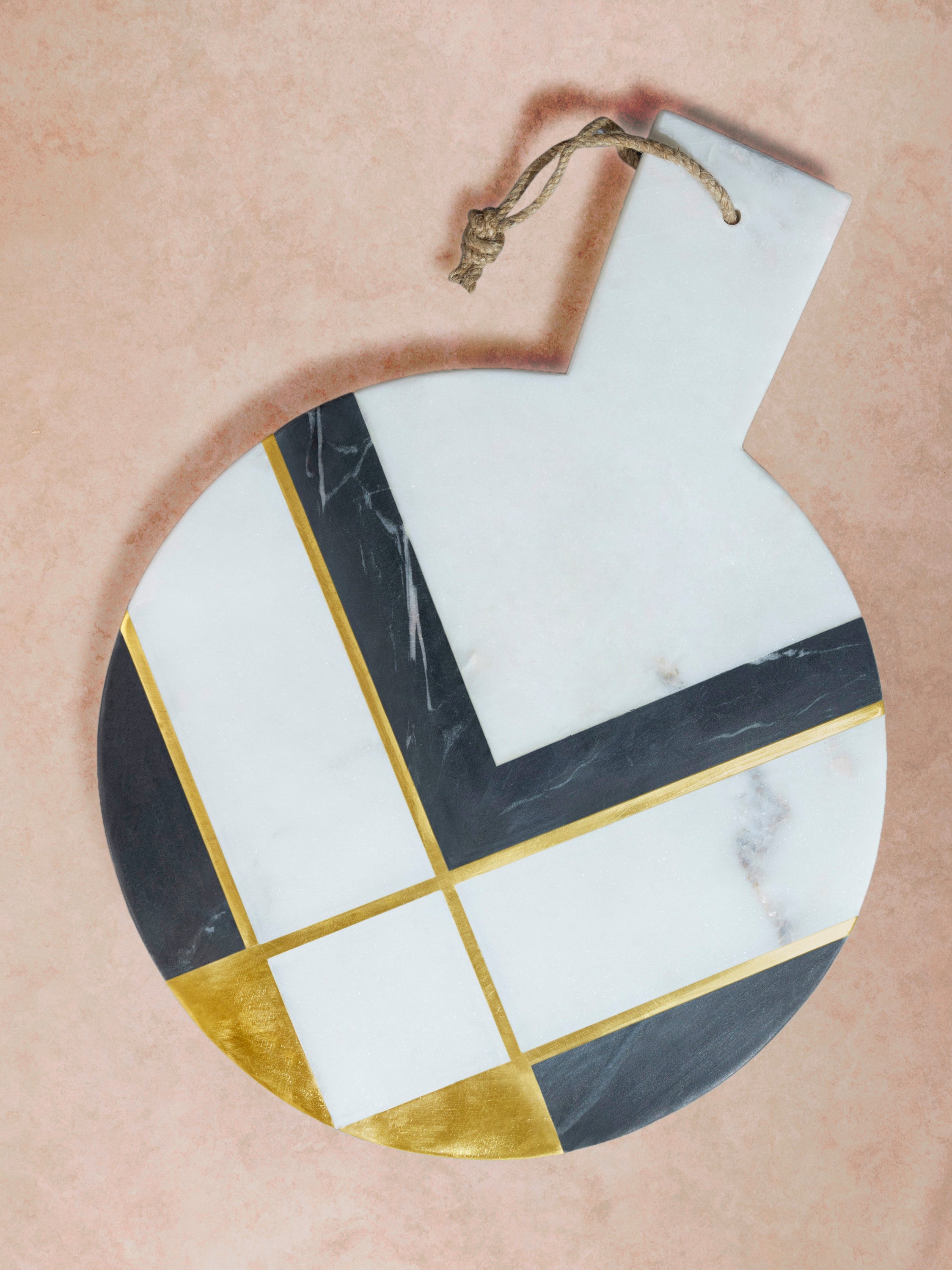 Round marble cheese board with geometric inlay featuring contrasting stone segments in white, black, and warm brown tones, presented in a clean top-down composition