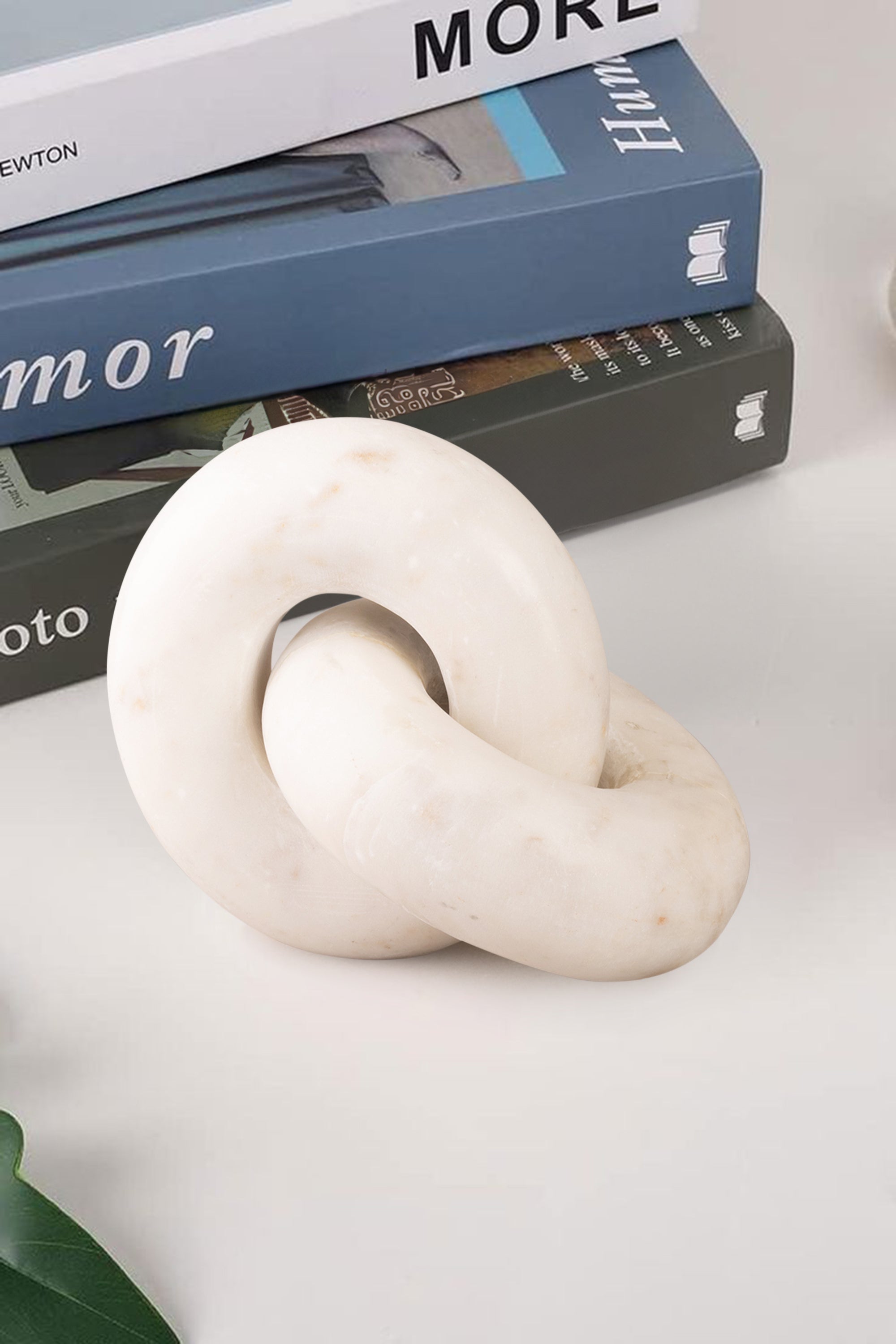 White marble knot with interlocking form displayed on a tabletop, emphasizing continuous curves and smooth finish