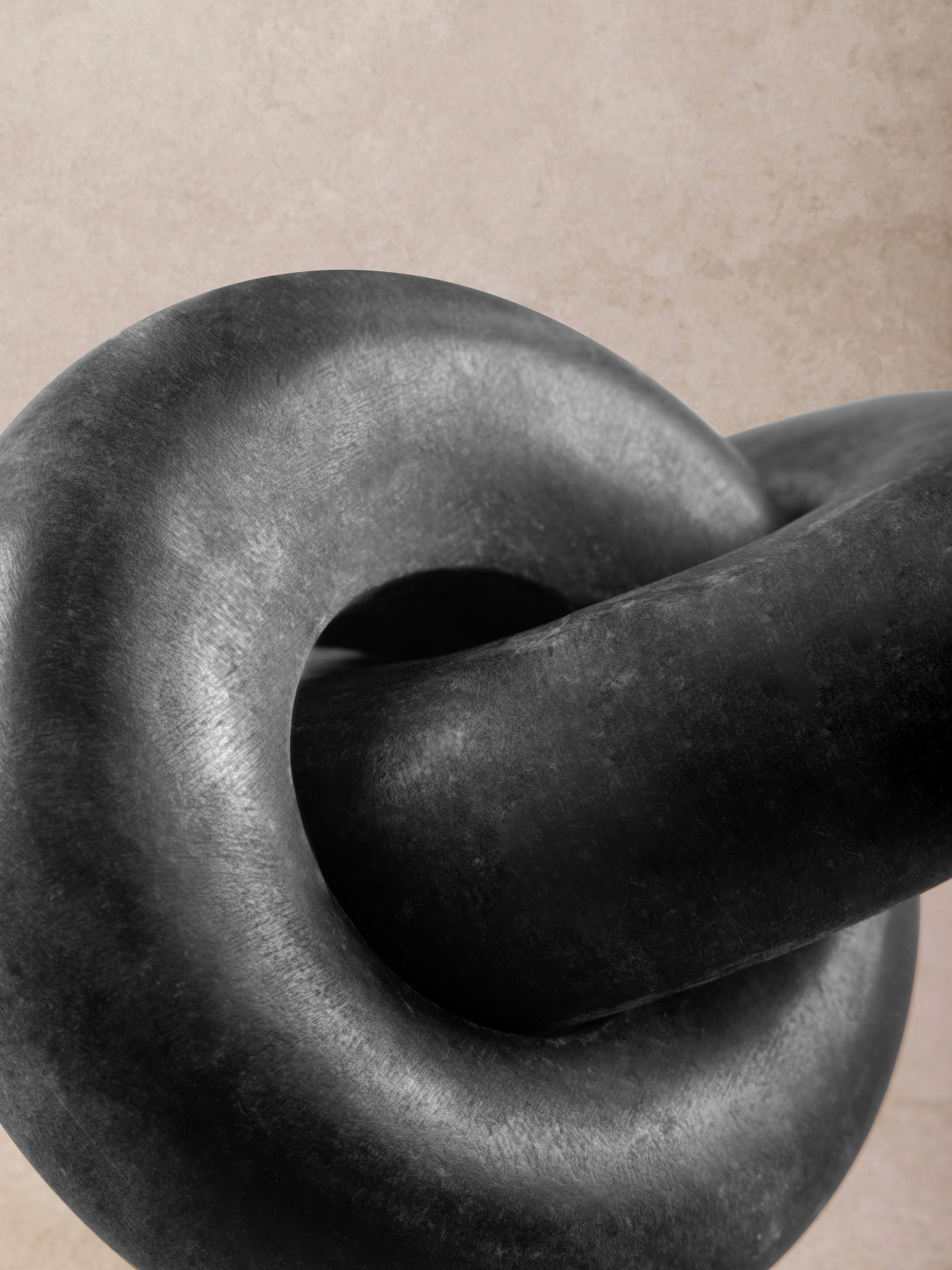 Close-up of black marble knot showing intertwined loops, smooth contours, and subtle tonal variation in the stone