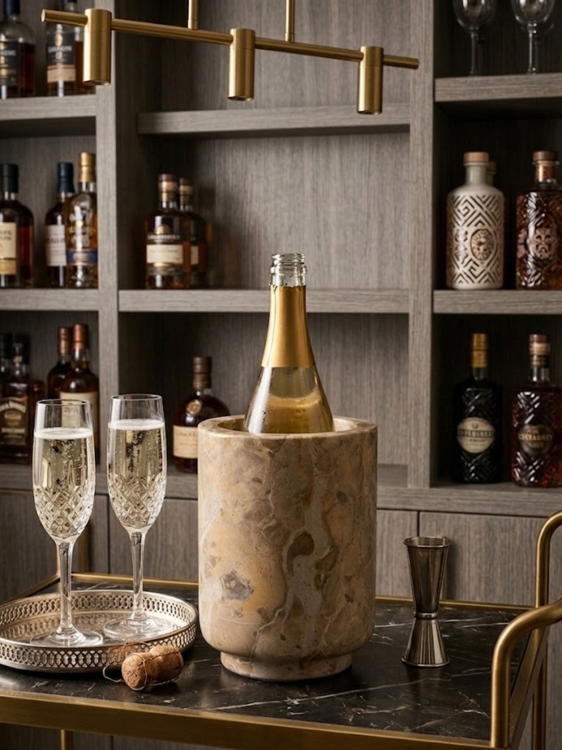 Chamonix brown onyx wine cooler styled on a marble kitchen island with champagne flutes and fresh berries, highlighting warm mineral veining and celebratory table styling.