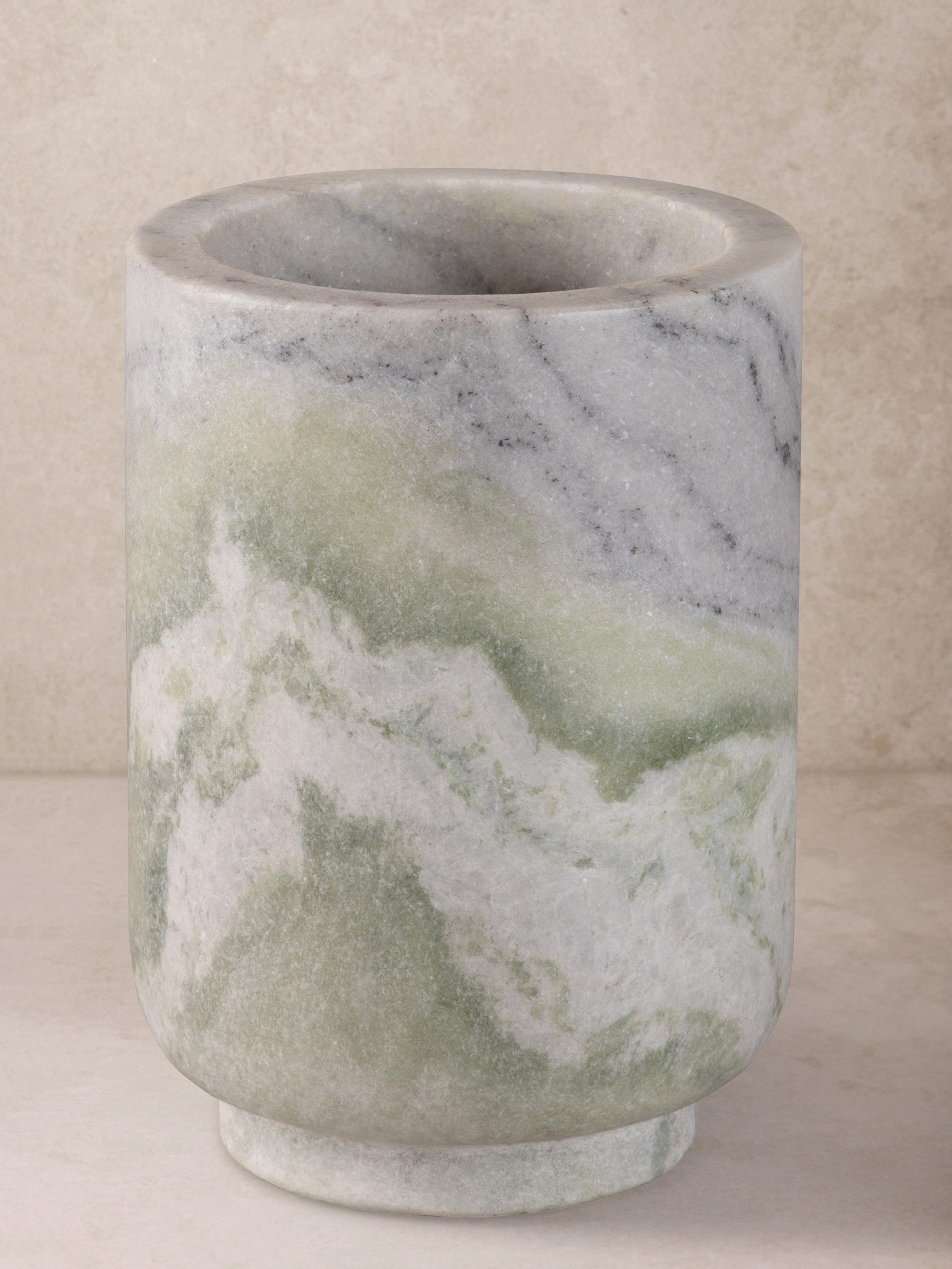 Chamonix wine cooler in green onyx with flowing veining and a cylindrical form, shown in a front-facing view.