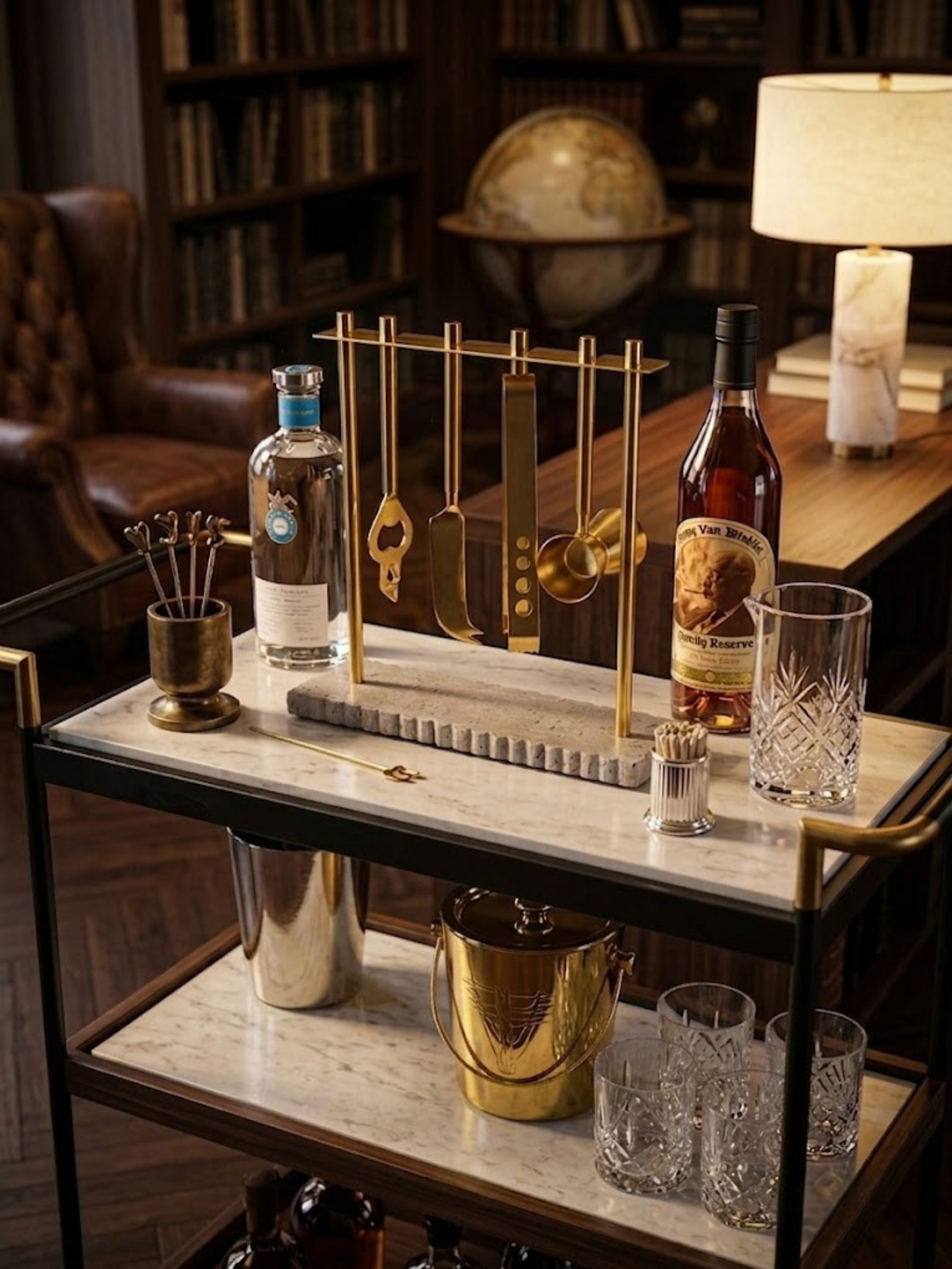 Jubel travertine bar tools arranged on an entertaining cart beside crystal decanters, showing the full tool set.