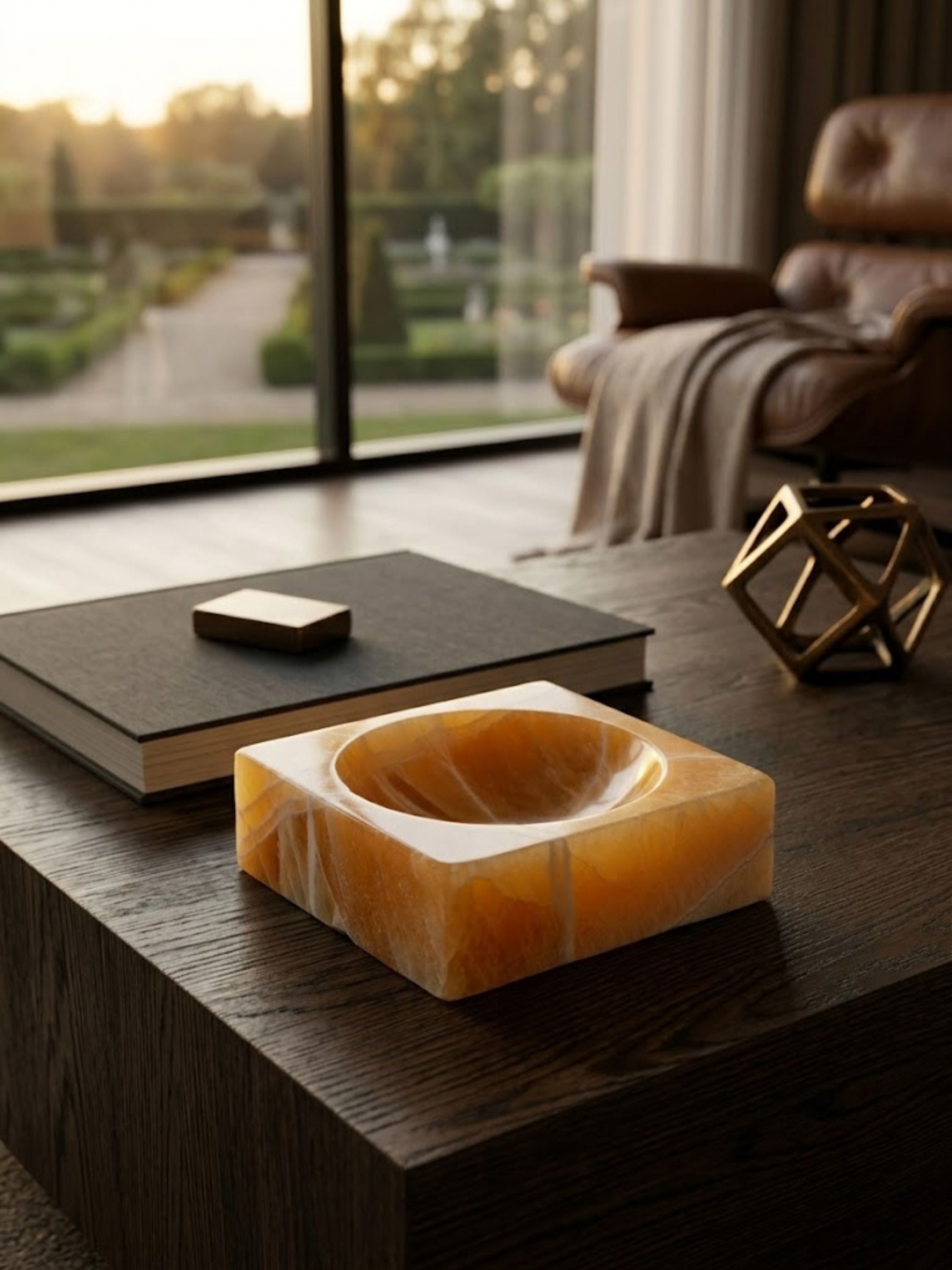 Marigold onyx decorative bowl displayed on a dark wood coffee table, showcasing its luminous mineral movement and sculptural form.