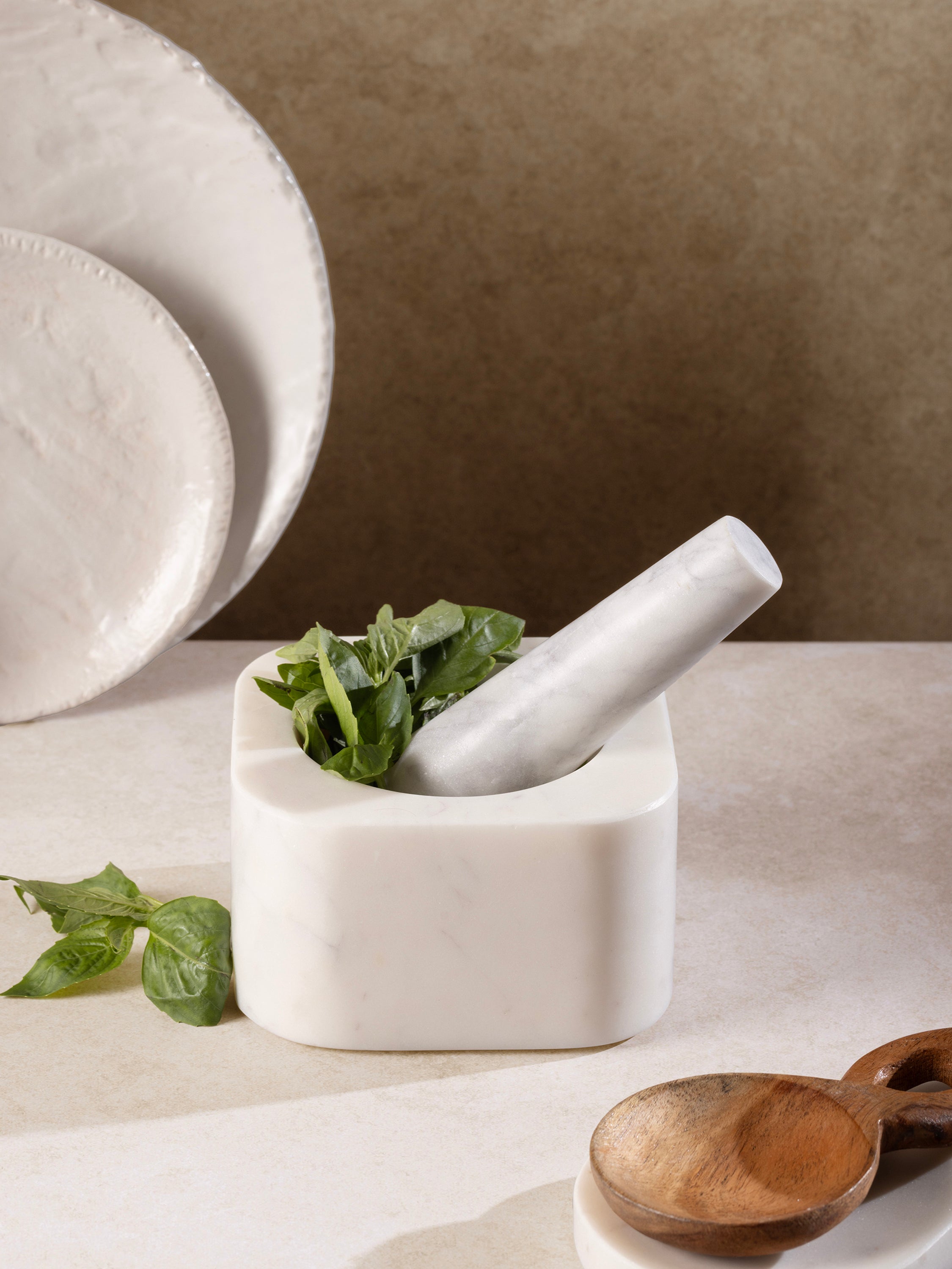 Mortar & pestle on kitchen counter with herbs nearby