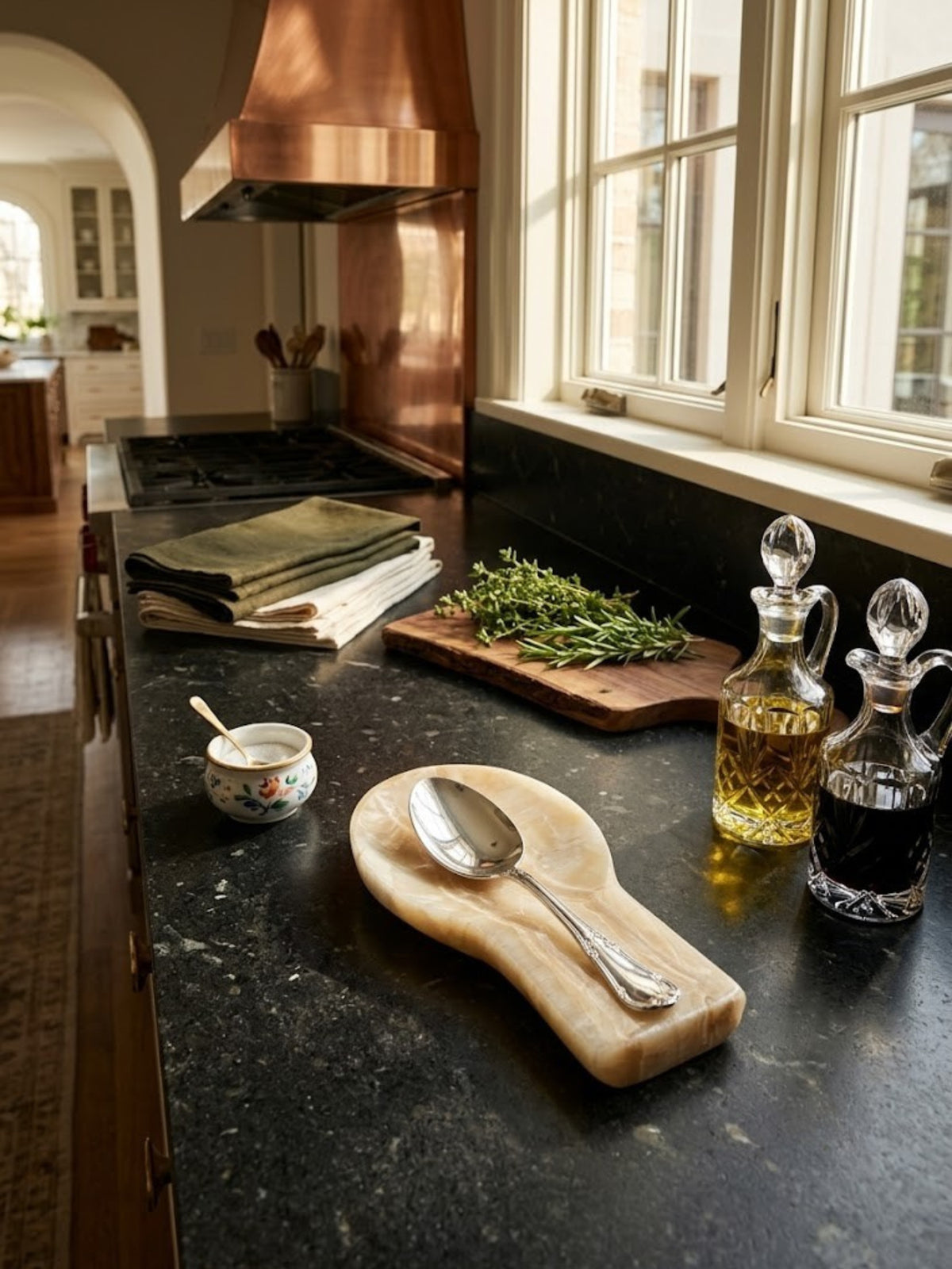 Machu Picchu onyx spoon rest with a spoon in the head, on a dark kitchen counter.