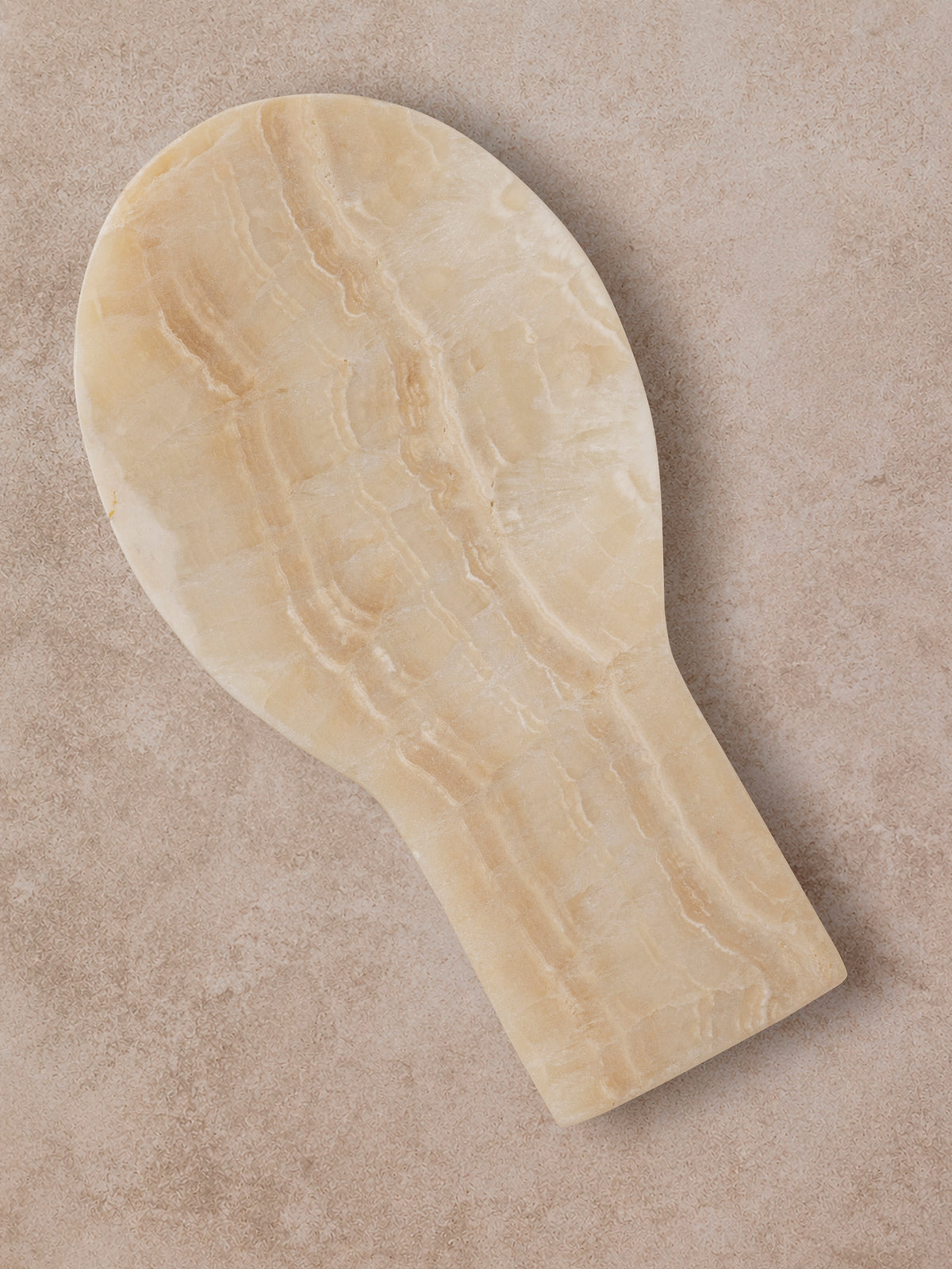 Machu Picchu onyx spoon rest in cream and honey, round head and straight body, shown top-down.