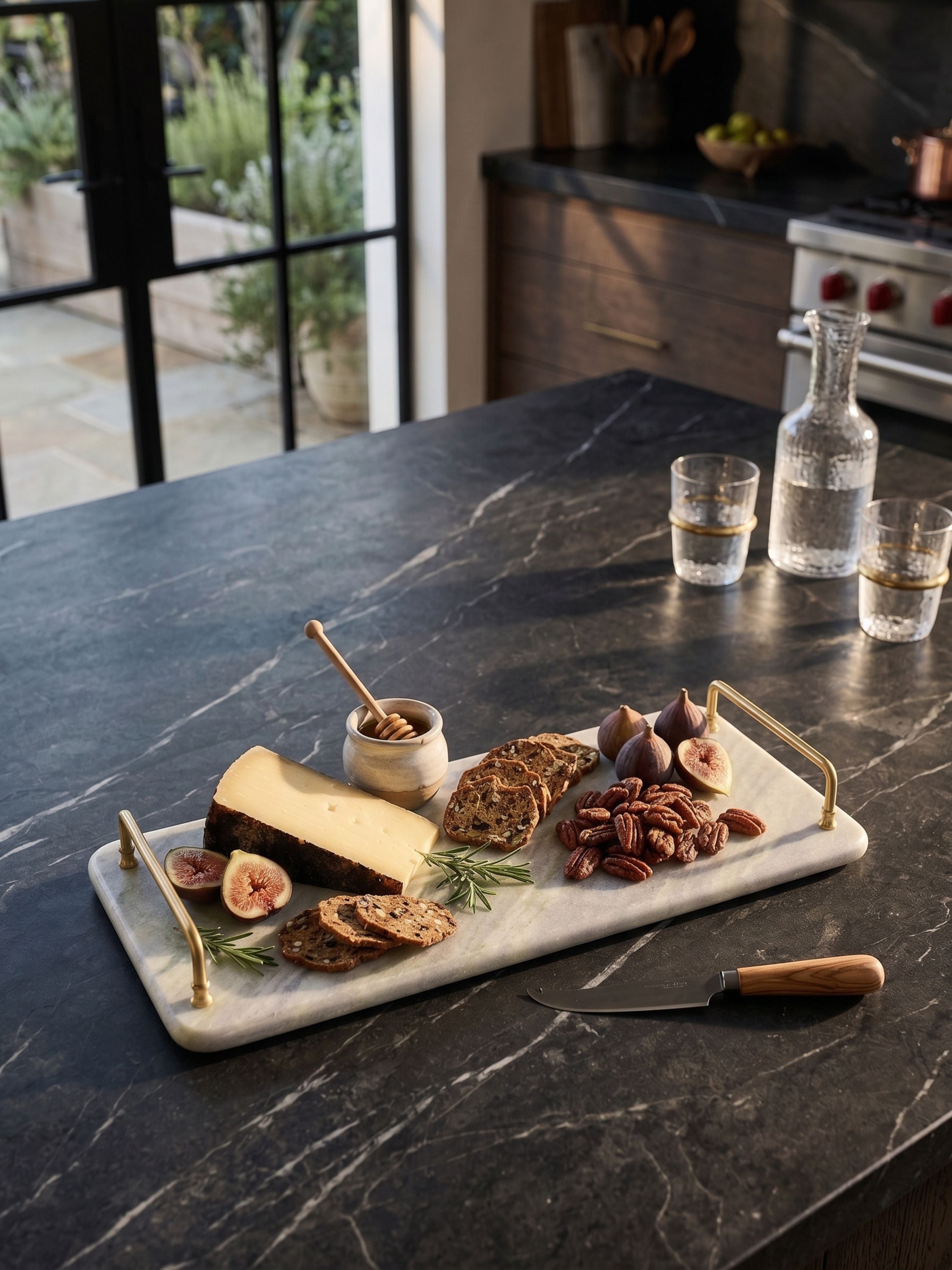 Green onyx serving tray with brass handles styled with cheese, nuts, and fruit on a kitchen countertop in an elevated serving setting