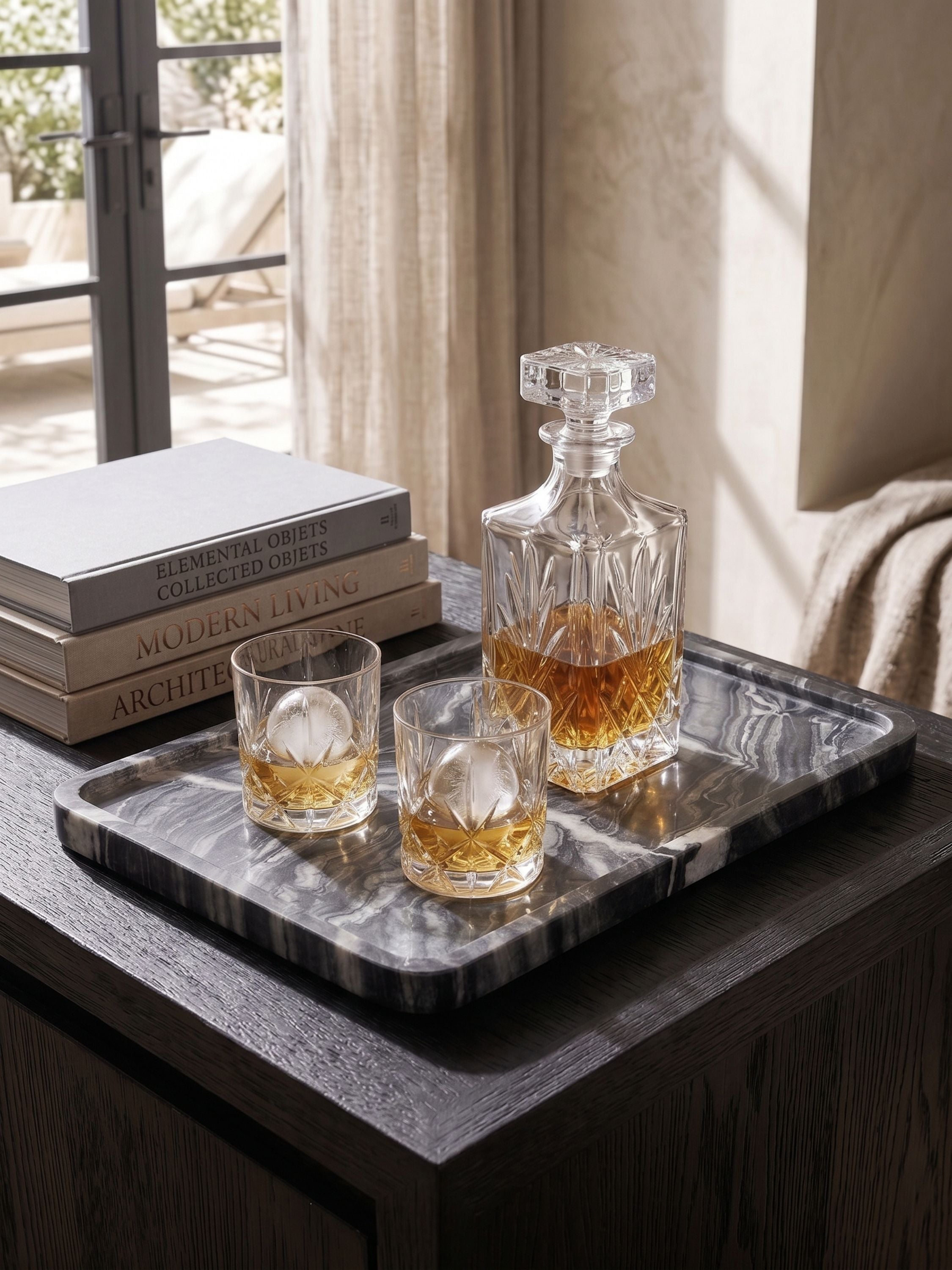 Black onyx serving tray styled with whiskey decanter and glasses on a side table in a refined living space
