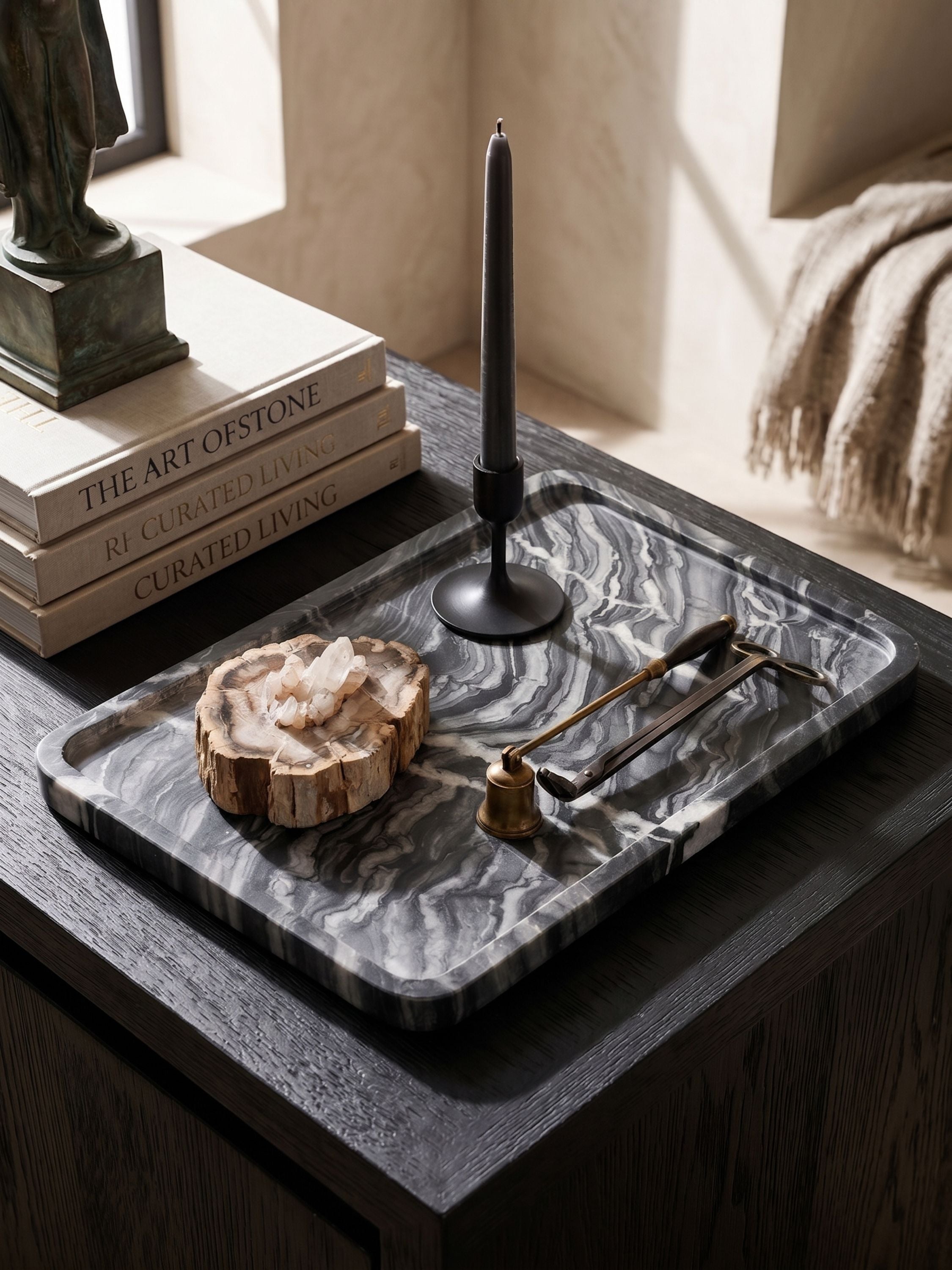 Black marble decorative tray styled with candle holder and objects on a console table in a warm neutral interior