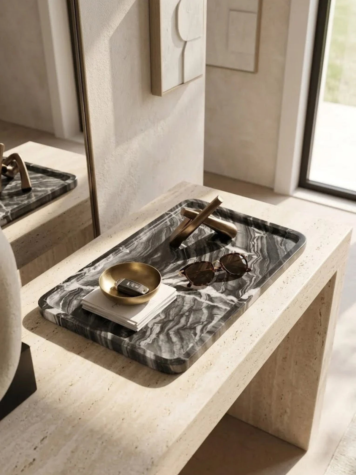 Frontier black onyx tray with rounded edges, holding a brass dish and glasses on a stone console.