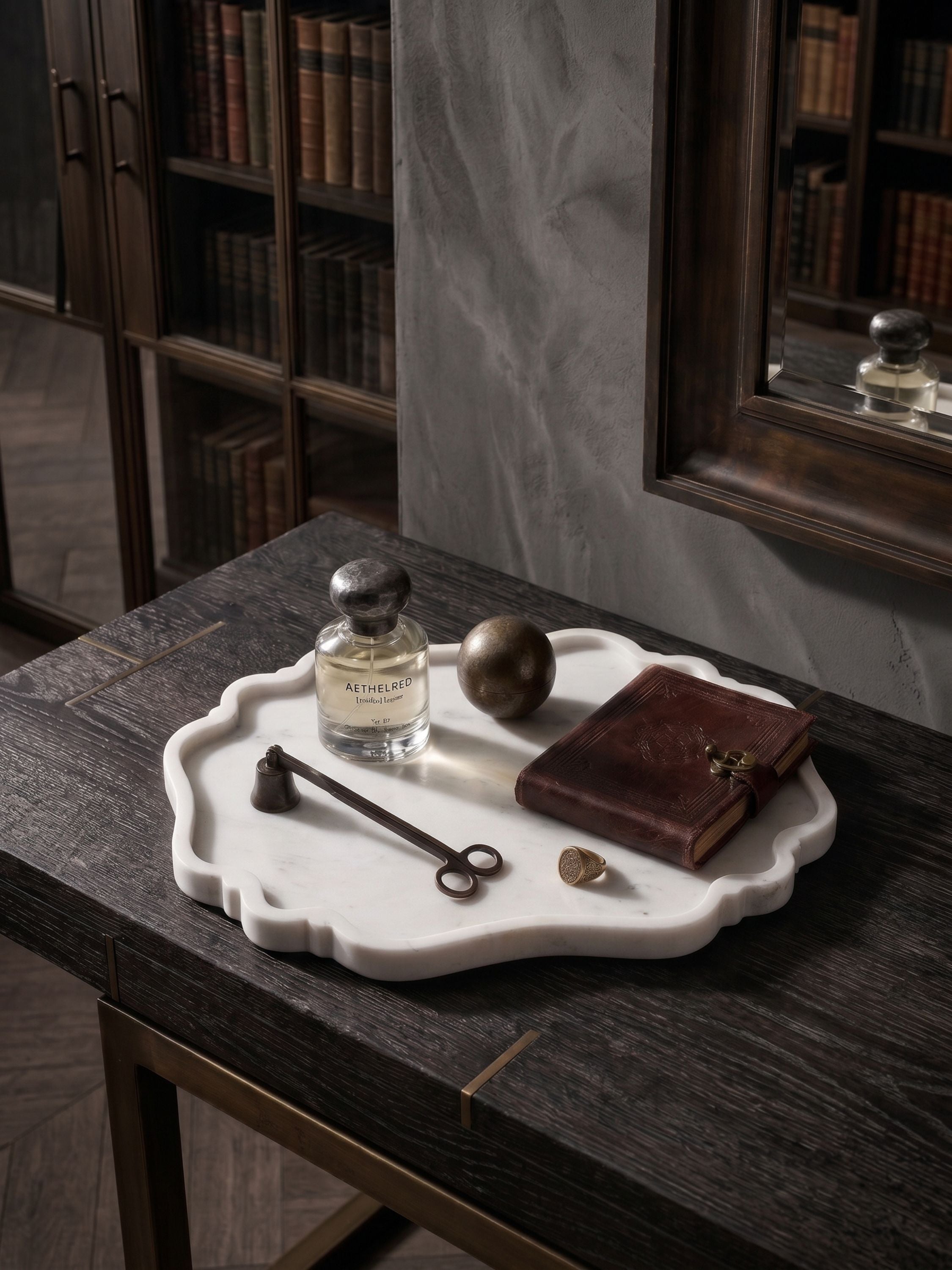 White marble scalloped decorative tray styled with perfume bottle, journal, and vintage objects on a dark wood console
