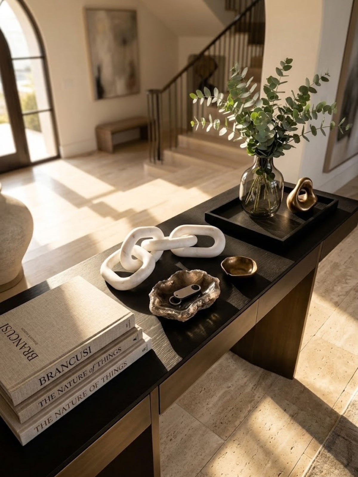 White marble chain-link sculpture styled on an entryway console table.