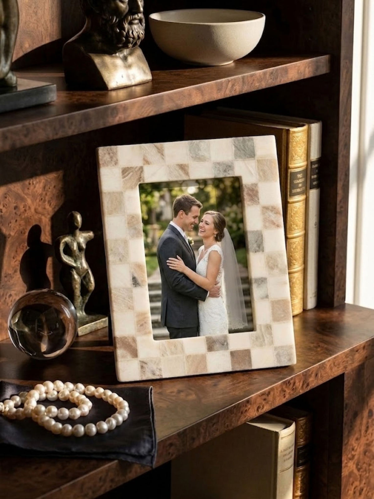 Beige and cream onyx mosaic picture frame, styled within a bookshelf among framed keepsakes.