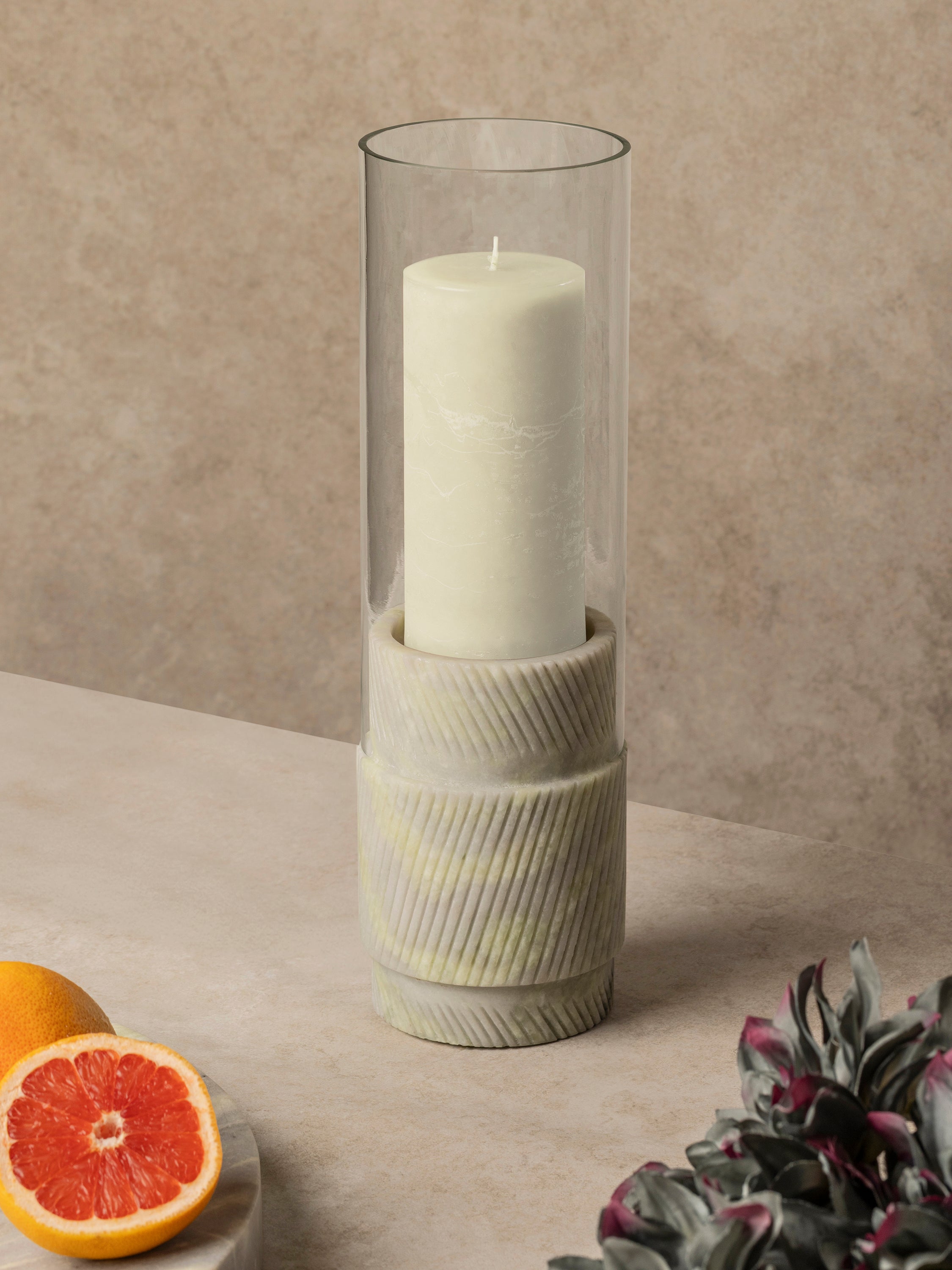 Green onyx hurricane candle holder with cylindrical glass insert and carved stone base, shown in a clean front-facing composition
