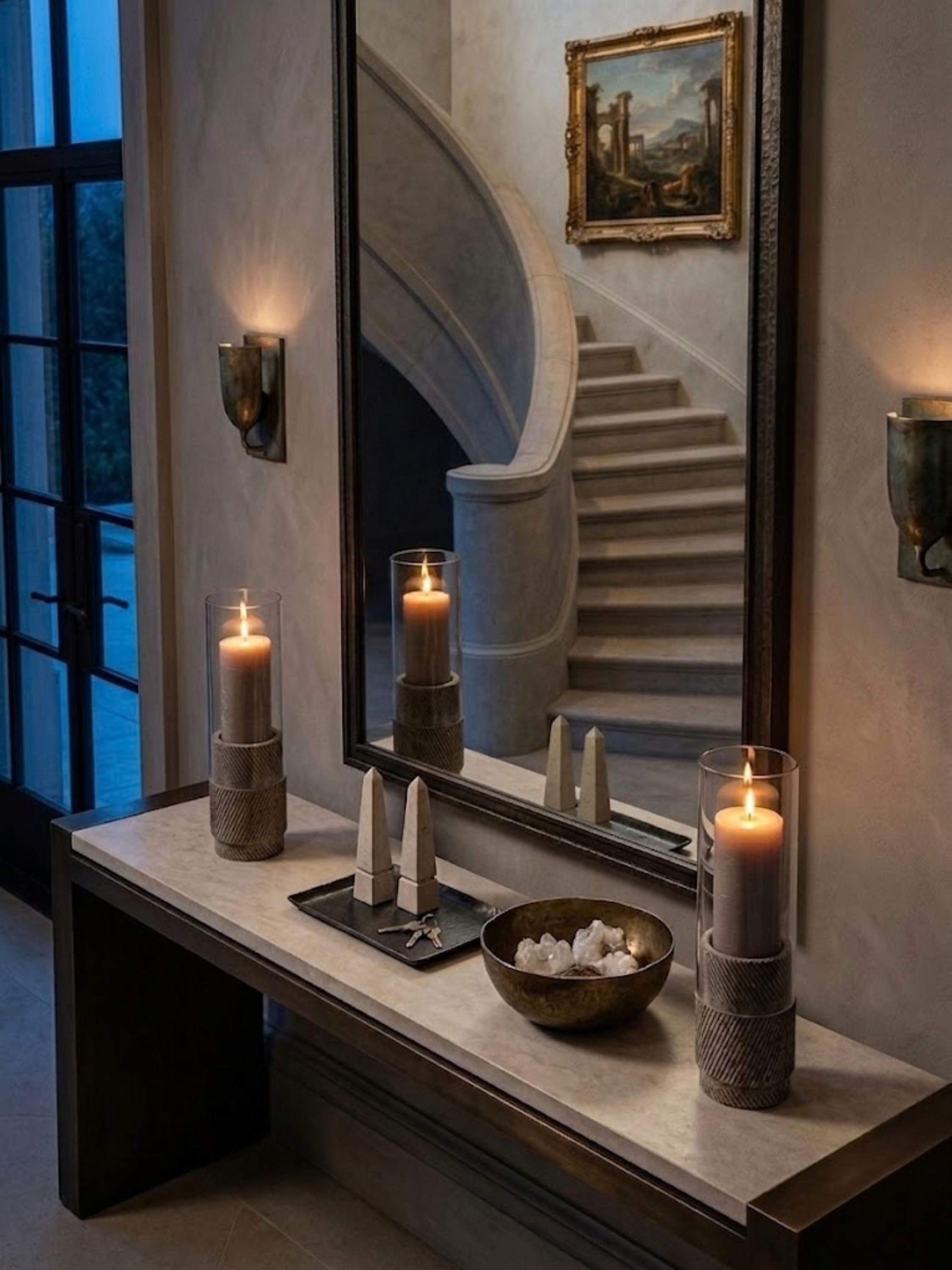 Estonia Brown Travertine hurricane candle holders displayed on an entryway console, creating a welcoming atmosphere with sculptural form, candlelight, and natural material richness.