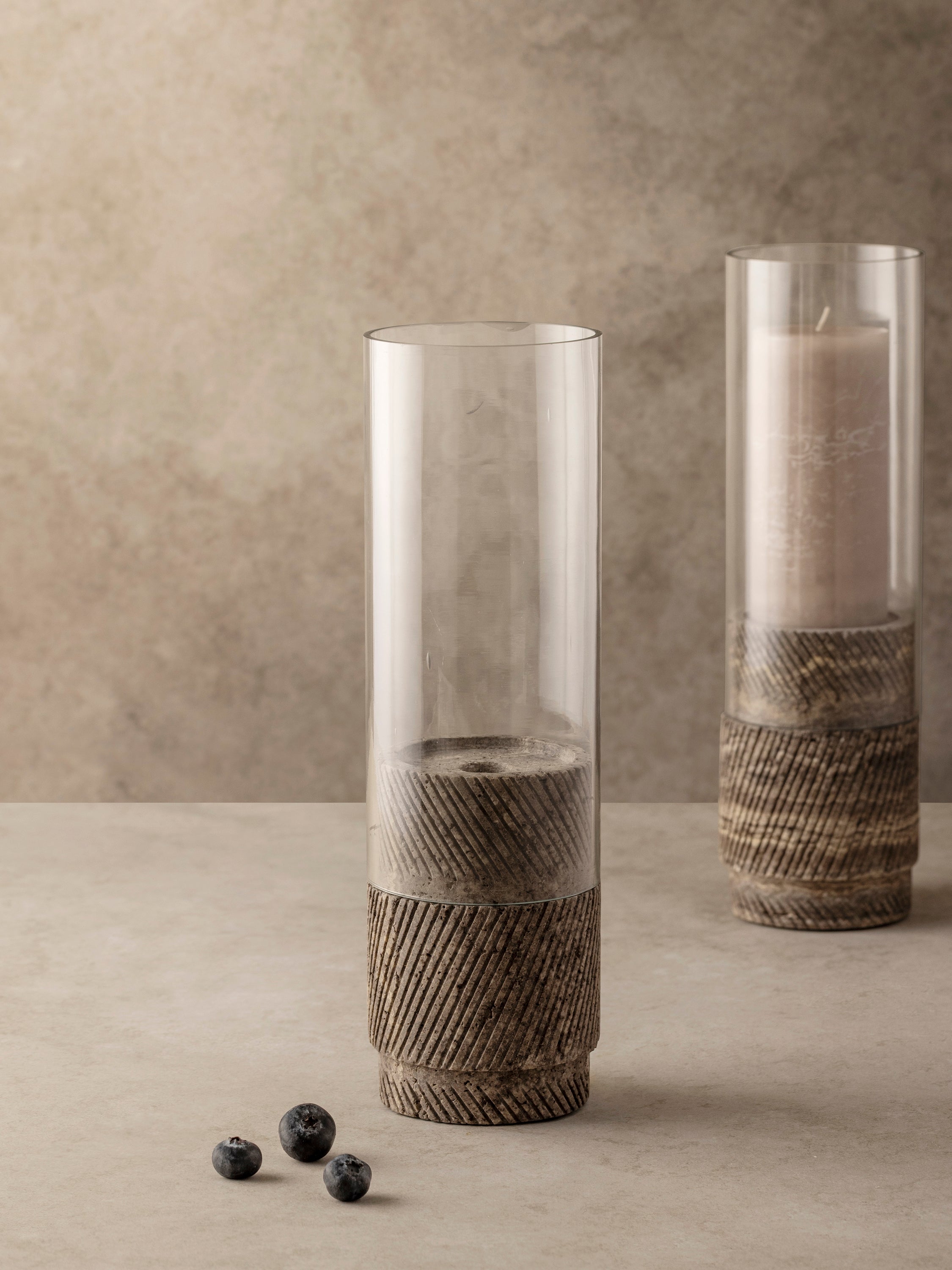 Set of two Estonia brown travertine hurricane candle holders shown together, highlighting textured stone bases and glass cylinder inserts