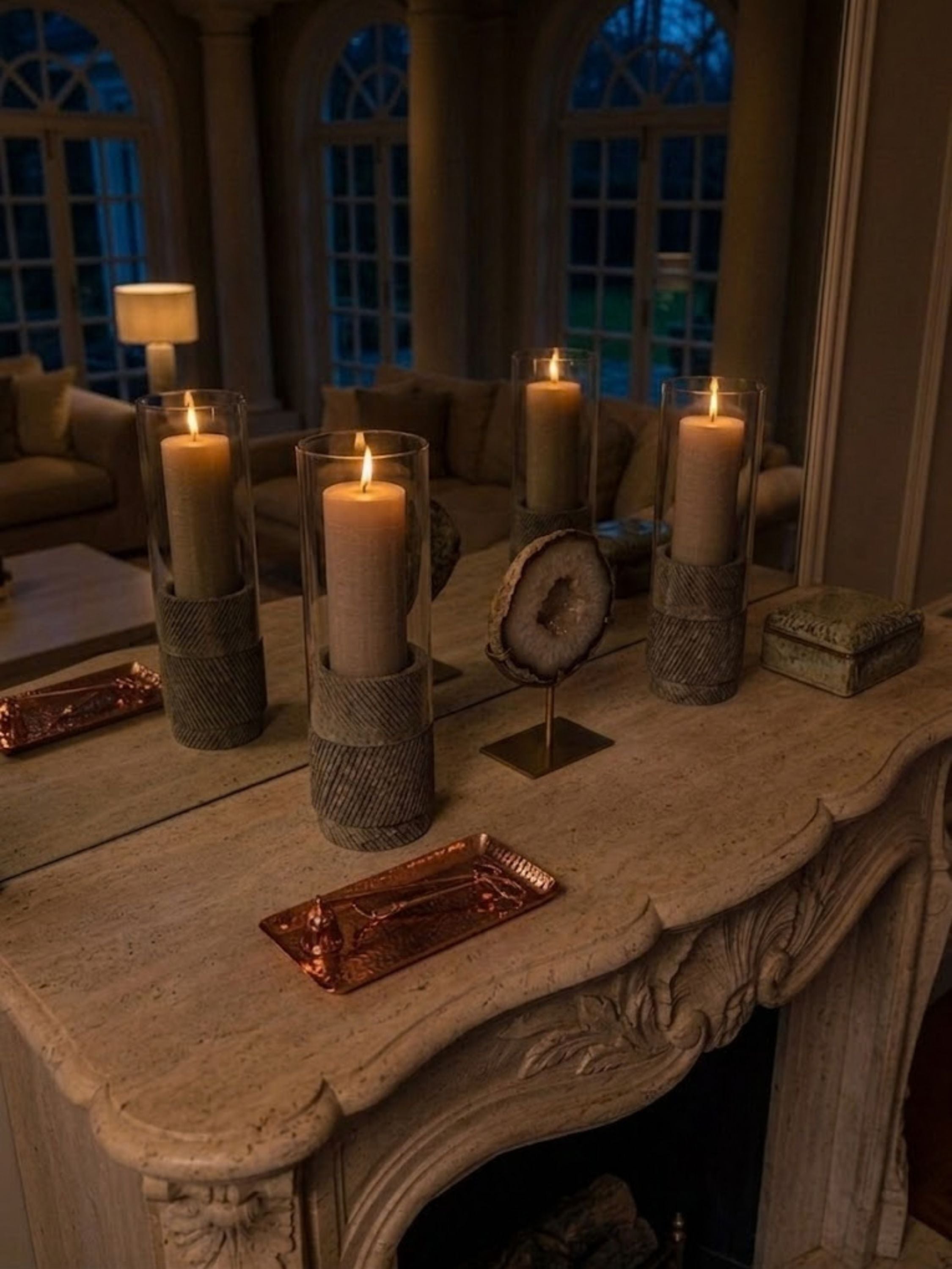 Estonia Brown Travertine hurricane candle holders arranged on a fireplace mantel, adding layered texture, soft illumination, and timeless architectural presence.