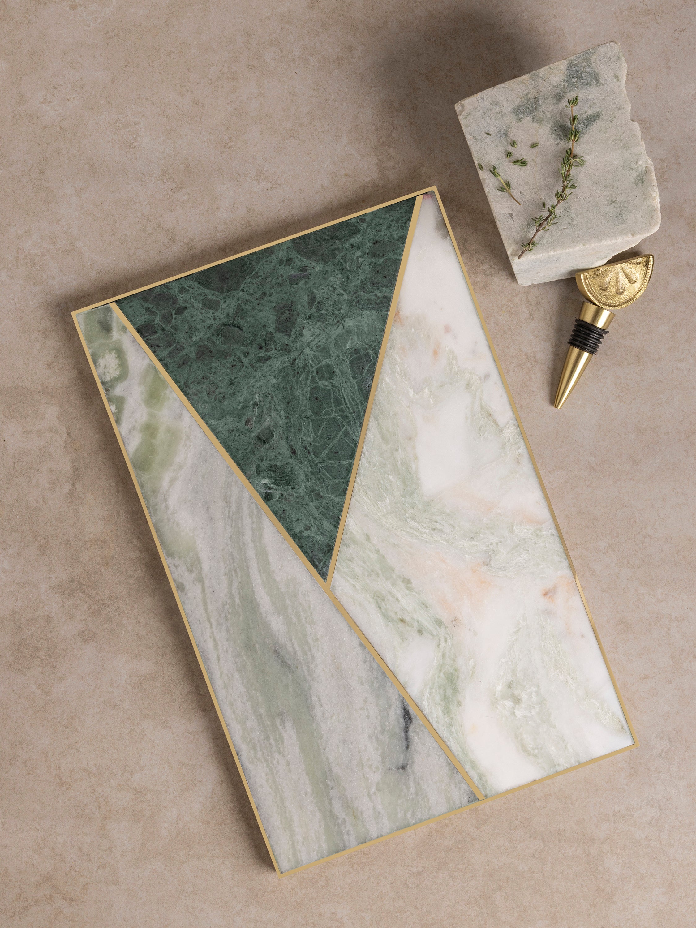 Rectangular marble cheese board with geometric multi-stone inlay pattern and brass accent seams, shown in a clean top-down composition