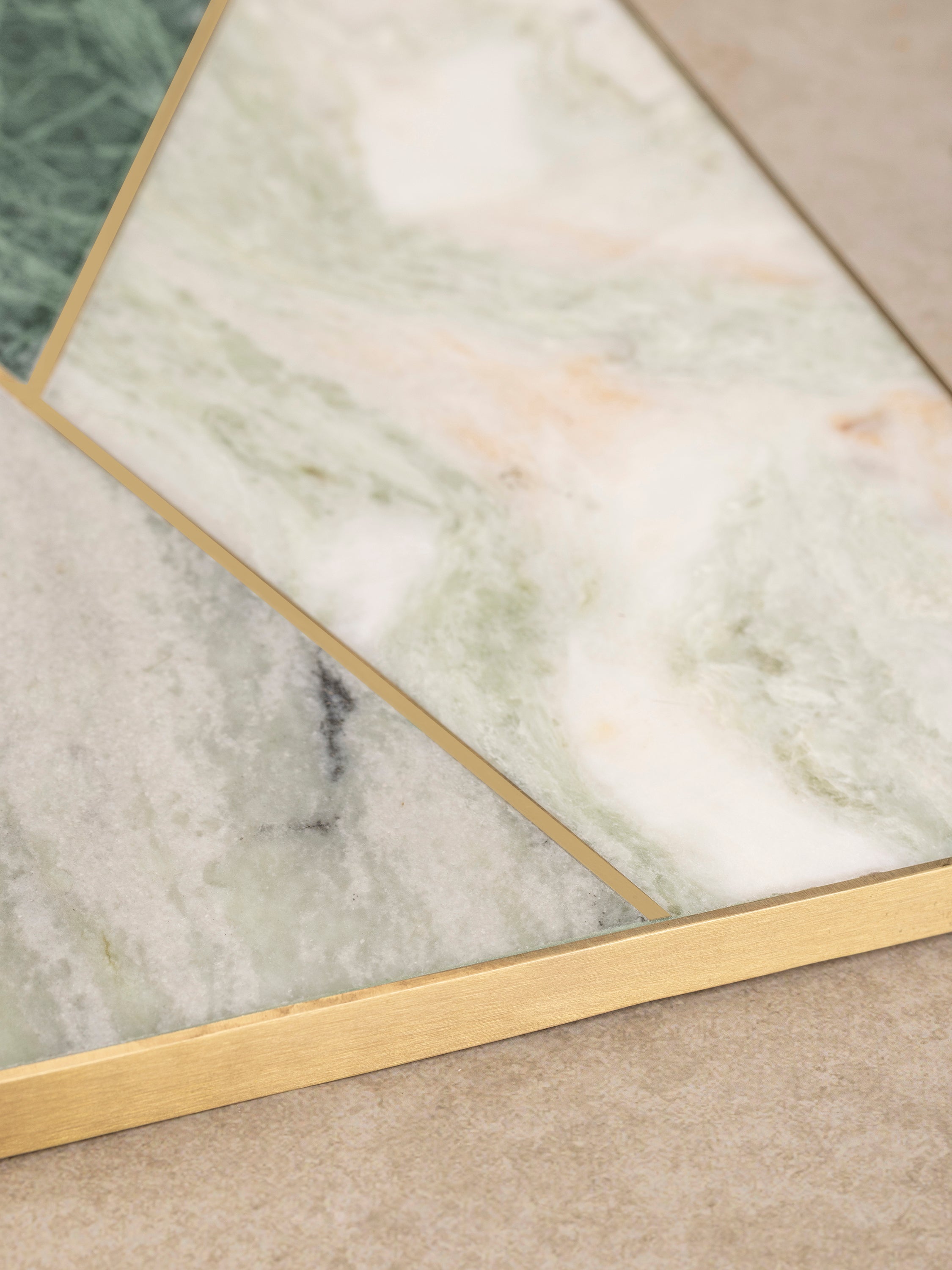 Close-up of Brno marble cheese board showing geometric stone inlay seams, brass detailing, and varied mineral tones across the surface