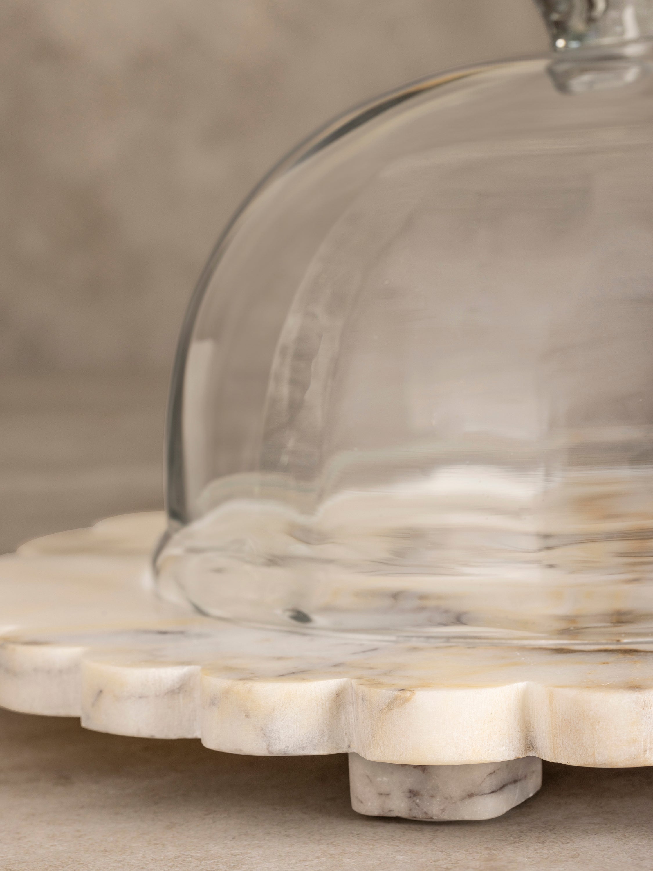 Kismet cloche board shown with glass dome elevated, highlighting organic scalloped stone edge and natural onyx surface veining